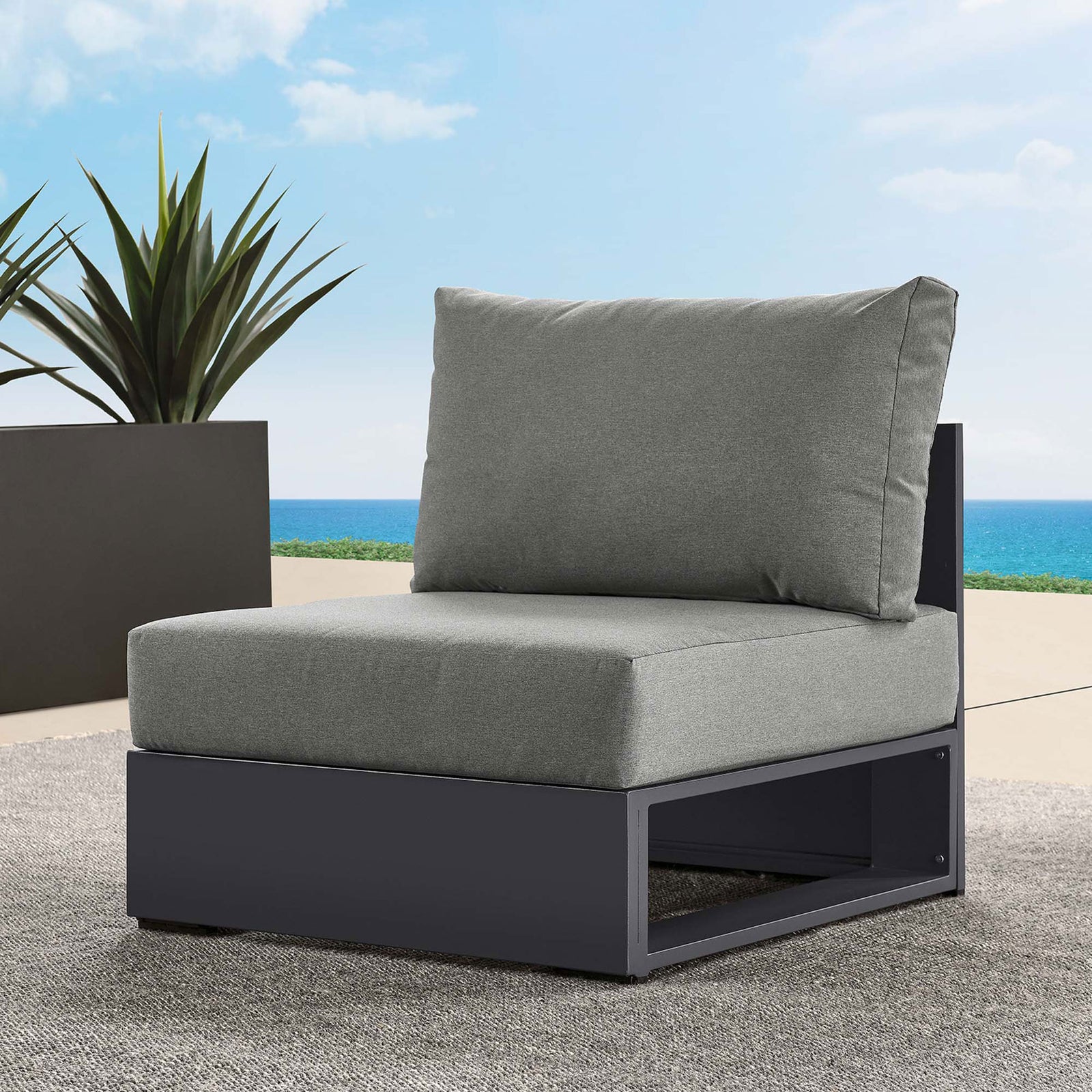 Charcoal Tahoe outdoor armless chair arranged on a patio overlooking the ocean with a modern planter || EEI-6628-GRY-CHA || front_angle_room