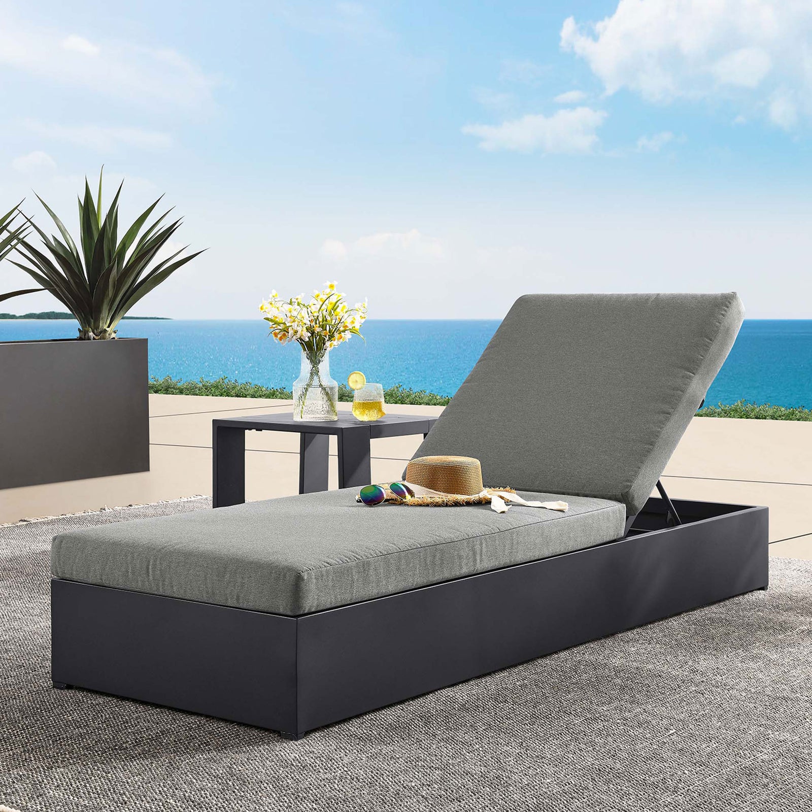 Charcoal chaise lounge styled on a coastal patio with side table, tray, and accessories for outdoor relaxation || EEI-6634-GRY-CHA || front_angle_room