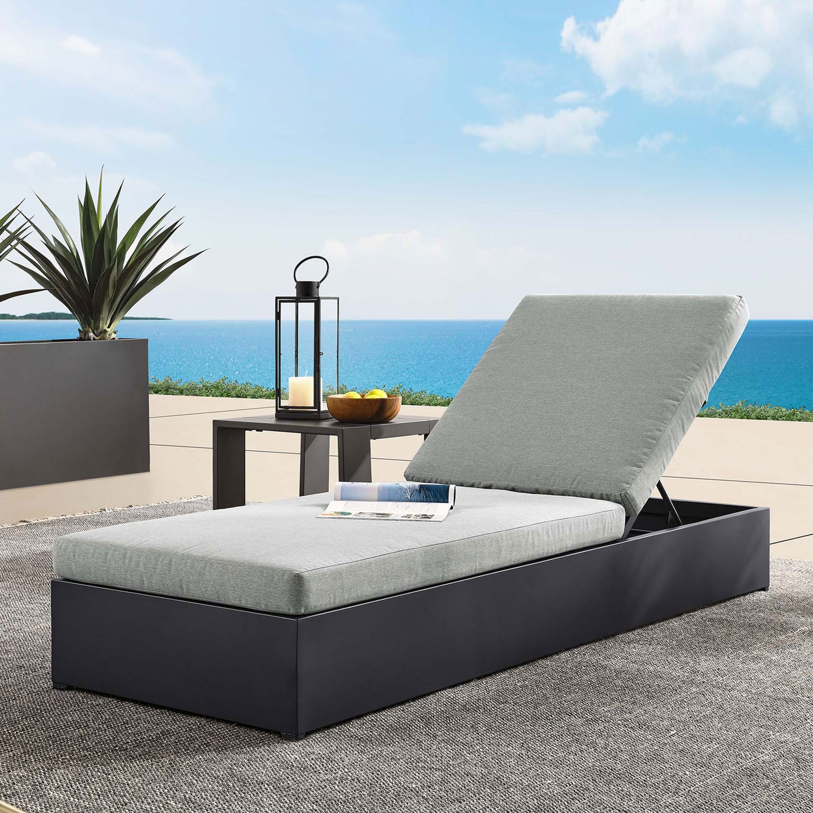 Light gray chaise lounge styled on a sunny terrace with side table and decor for outdoor lounging || EEI-6634-GRY-GRY || front_angle_room