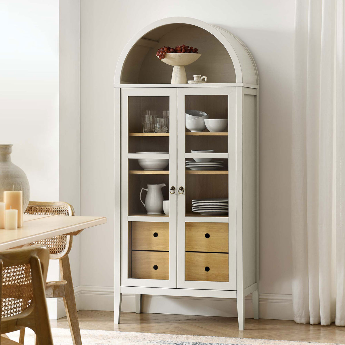 White oak arched cabinet styled in a bright dining room with dishes and decor on display || EEI-6639-WHI-OAK || front_angle_room
