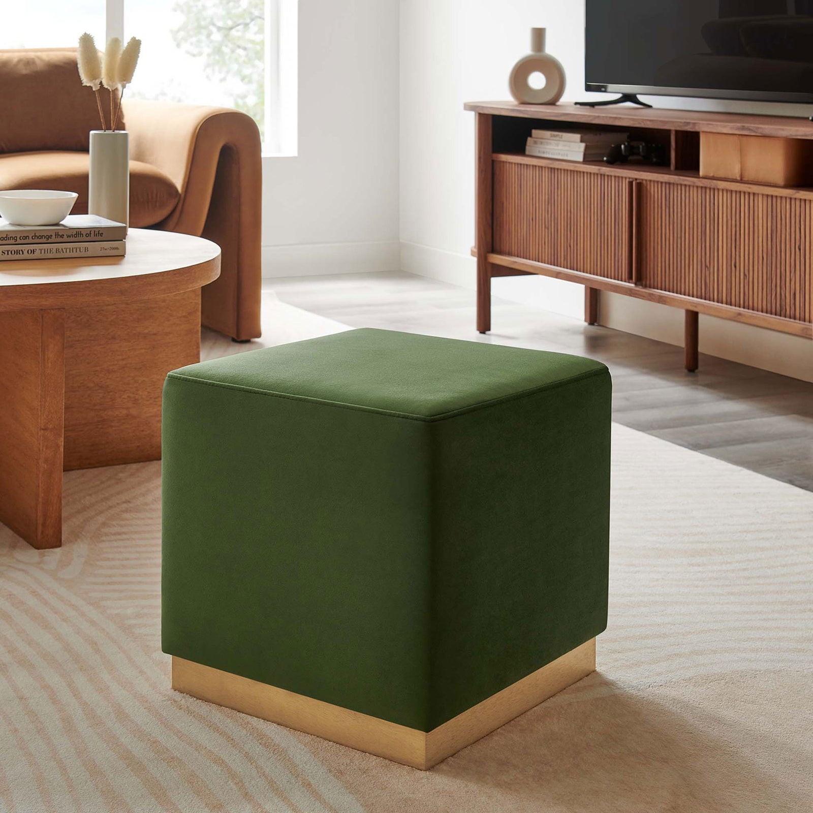 Moss green velvet ottoman accenting a modern living room with warm wood decor || EEI-6640-MOG-NAT || front_angle_room