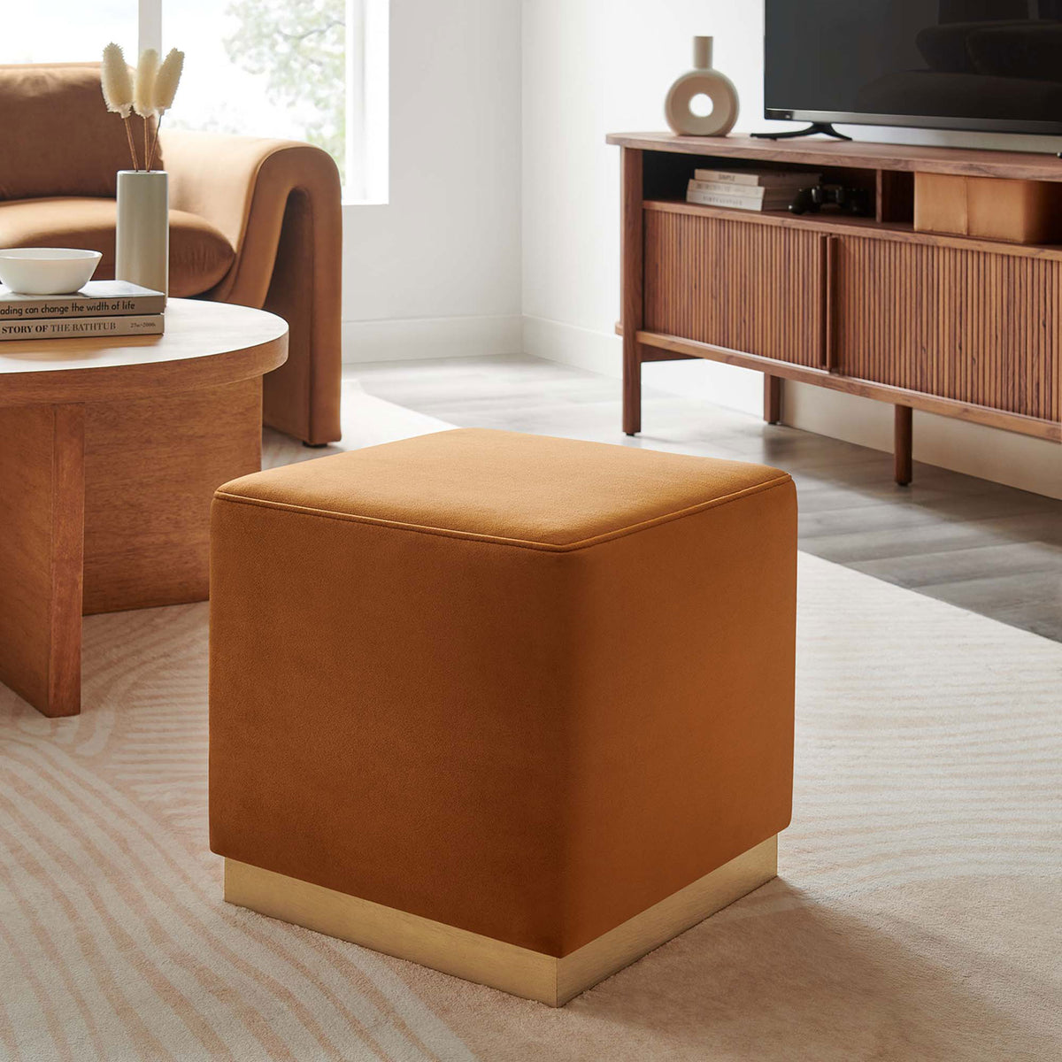 Rust velvet ottoman adding warm color to a modern living room with wood furniture and soft rug || EEI-6640-RUS-NAT || front_angle_room