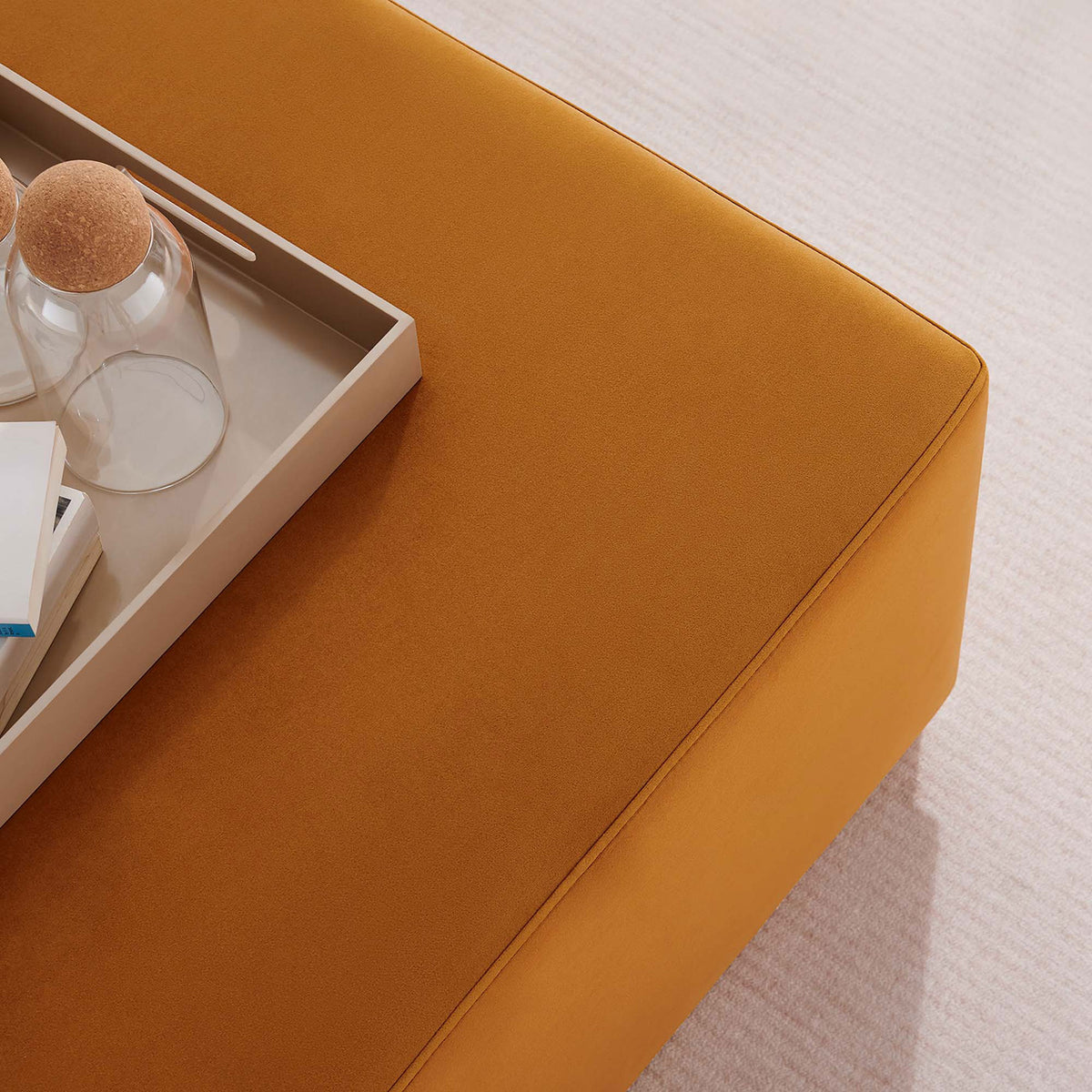 Rust velvet ottoman topped with tray, books, and glass decor on soft neutral area rug || EEI-6643-RUS-NAT || detail_room