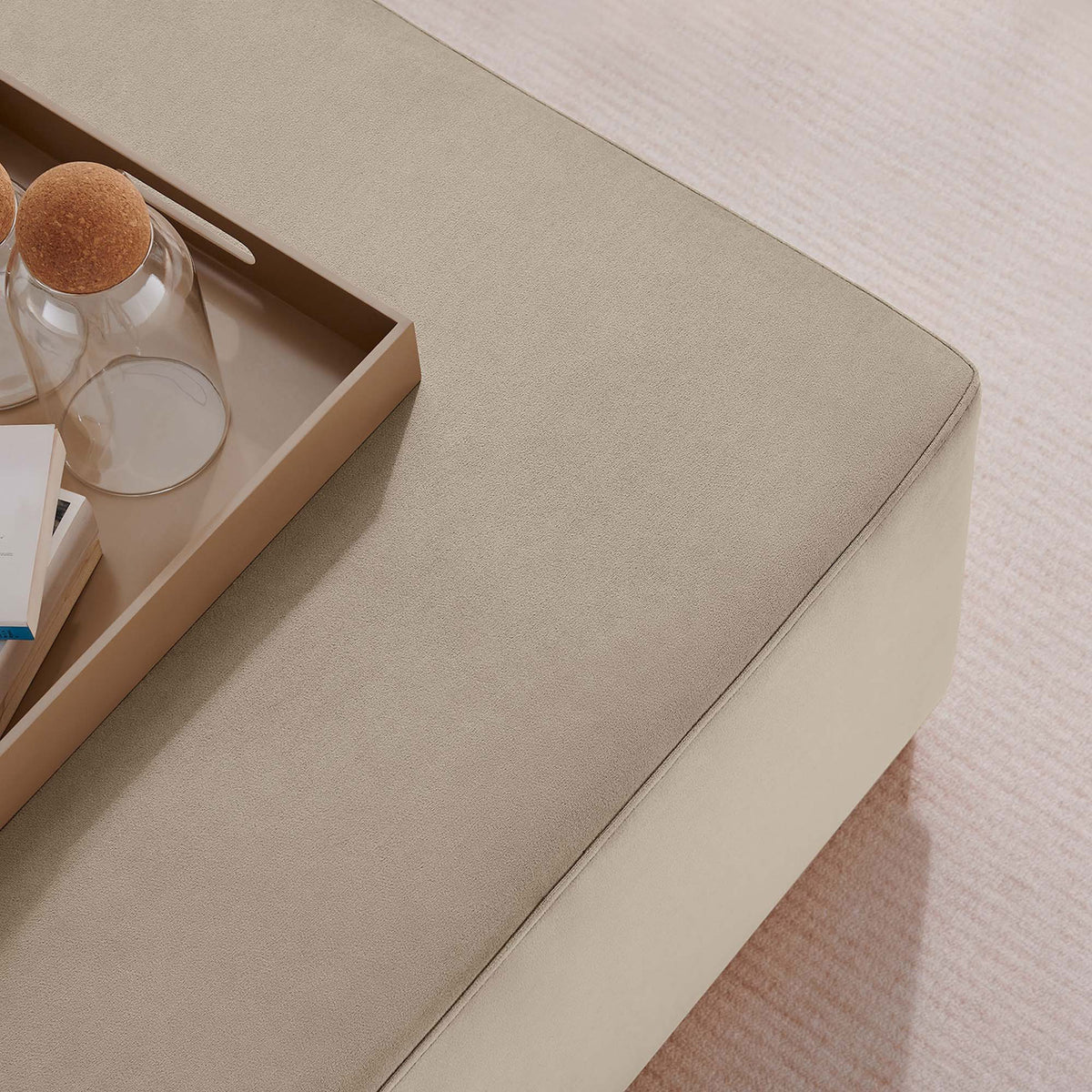 Taupe velvet ottoman top styled with tray, books, and decor on a soft textured area rug || EEI-6643-TAU-NAT || detail_room