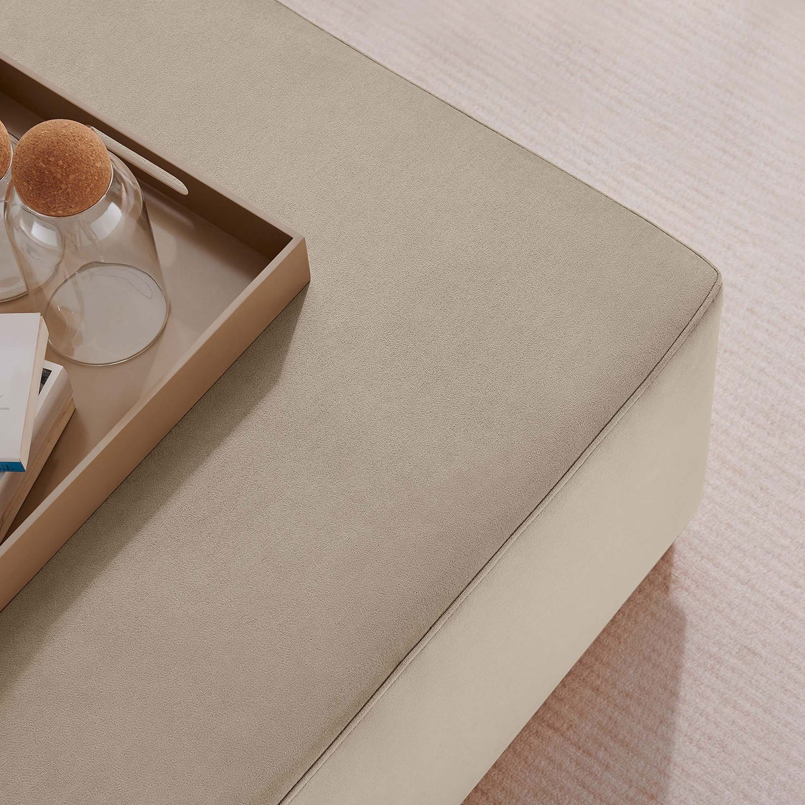 Taupe velvet ottoman top styled with tray, books, and decor on a soft textured area rug || EEI-6643-TAU-NAT || detail_room