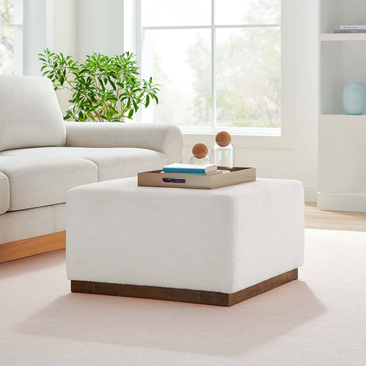 Cloud boucle ottoman anchors an airy living room as a modern coffee table and extra seating. || EEI-6644-CLO-WAL || front_angle_room