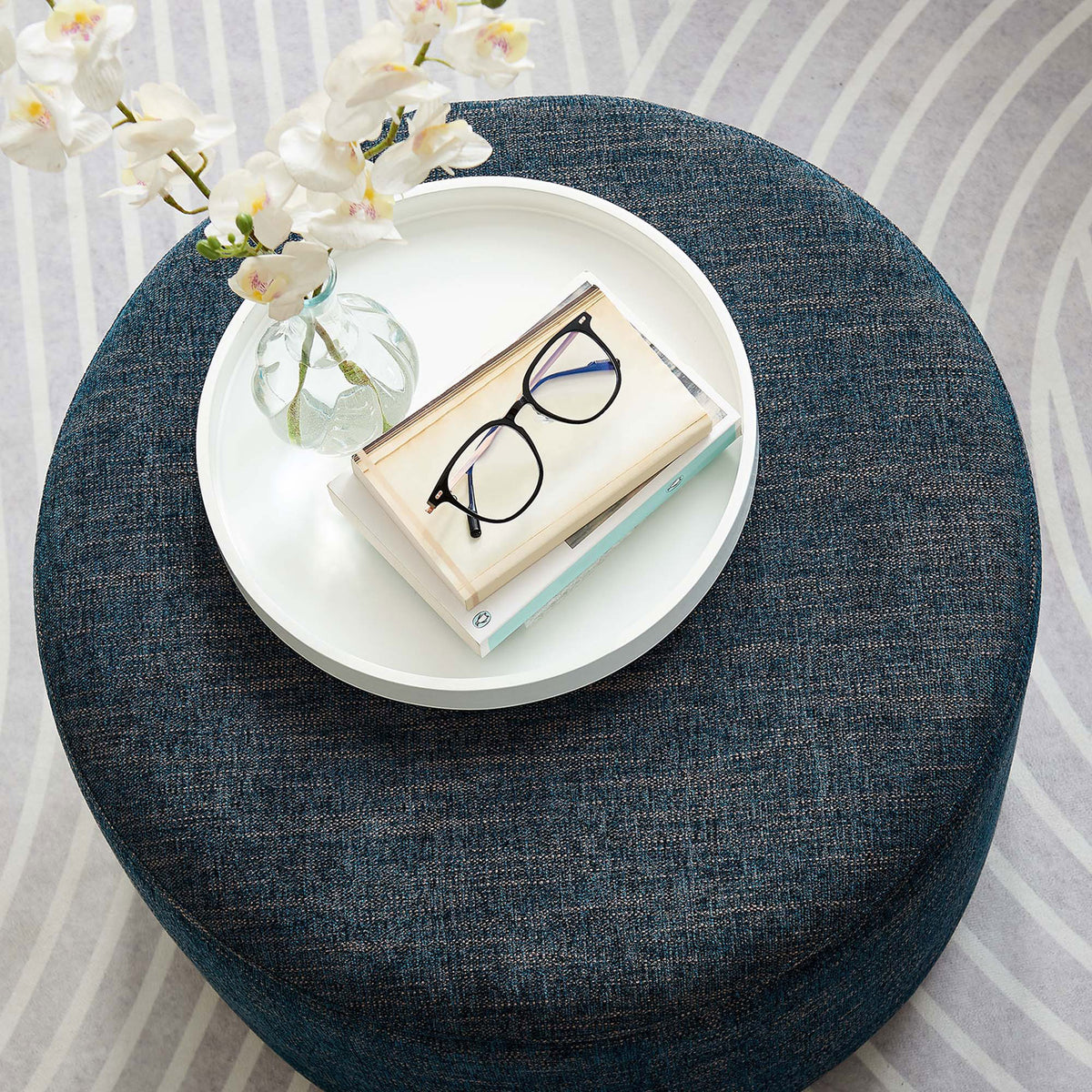 Heathered azure ottoman doubles as a compact coffee table on a patterned rug with decor accents || EEI-6645-HEA || top_angle_room