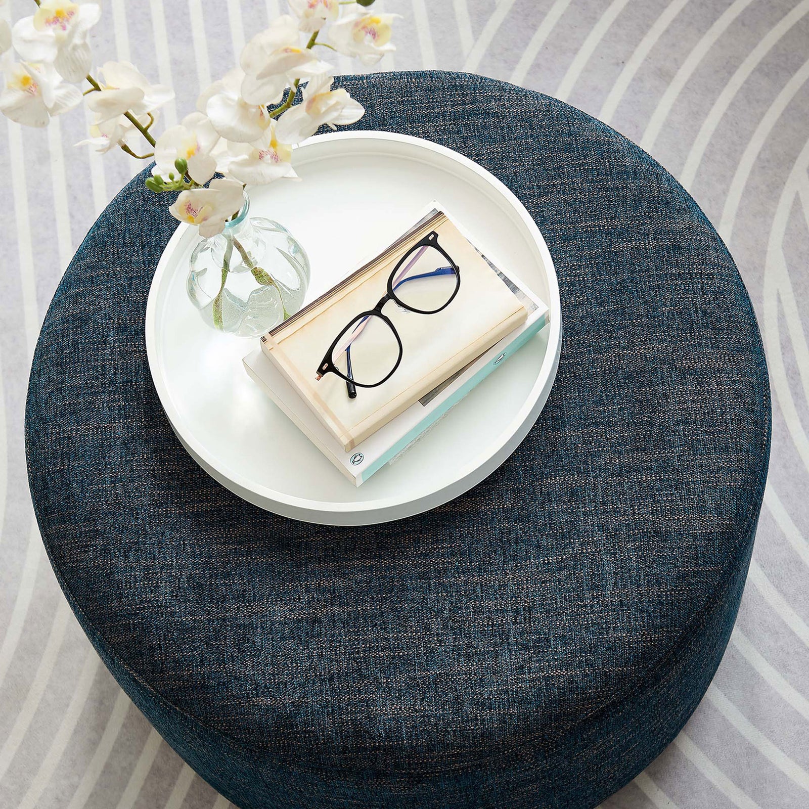 Heathered azure ottoman doubles as a compact coffee table on a patterned rug with decor accents || EEI-6645-HEA || top_angle_room