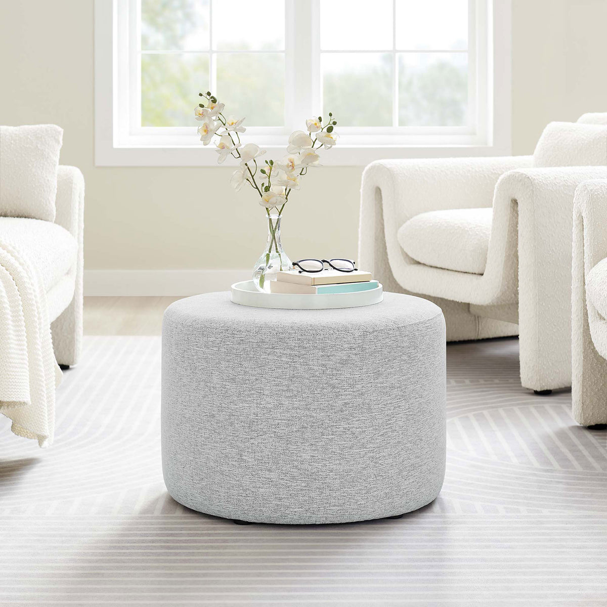 Heathered light gray round ottoman anchoring a bright contemporary living room seating arrangement || EEI-6645-HLG || front_room