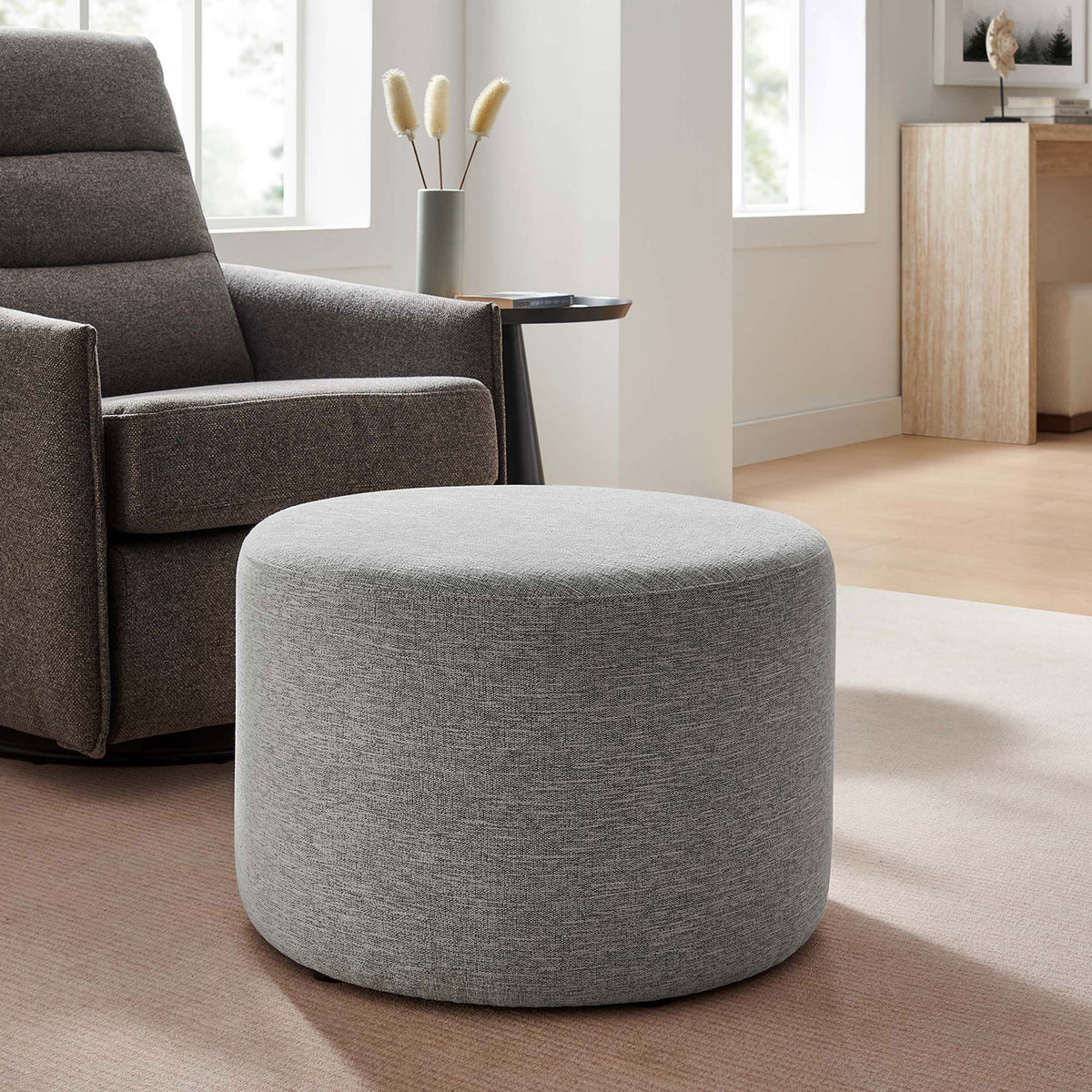 Versatile round gray ottoman paired with a lounge chair, adding soft texture and extra comfort to the room || EEI-6645-HLG || front_angle_room