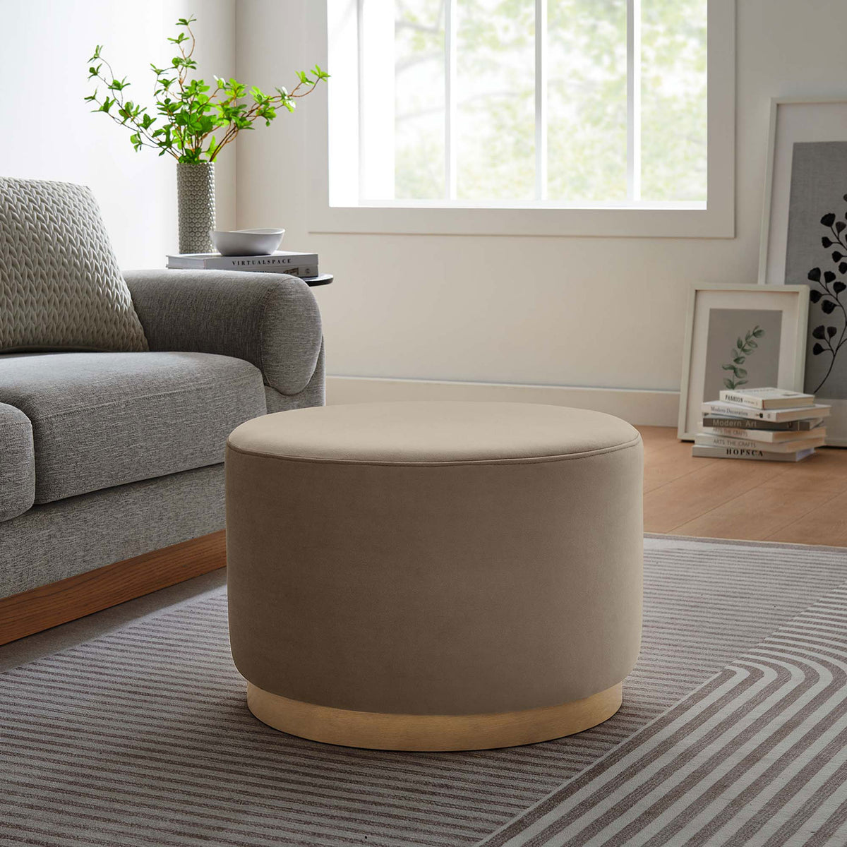 Round taupe ottoman beside a gray sofa, adding soft texture and extra seating to the living room || EEI-6646-TAU-NAT || front_angle_room