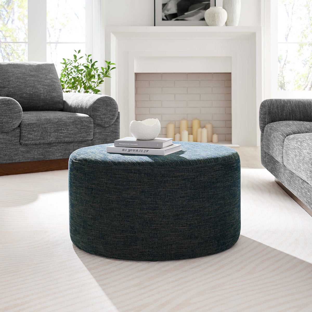 29 inch azure ottoman styled as a living room coffee table with books and decor on a light rug || EEI-6647-HEA || front_angle_room