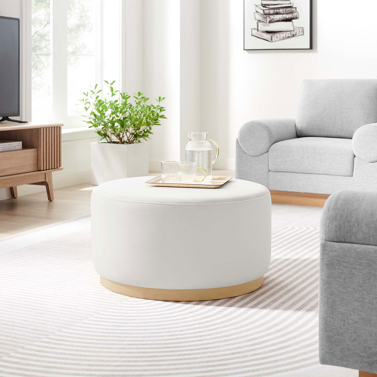 Tilden 29 inch round velvet ottoman serving as a coffee table in a light filled contemporary living room || EEI-6648-ALA-NAT || front_angle_room