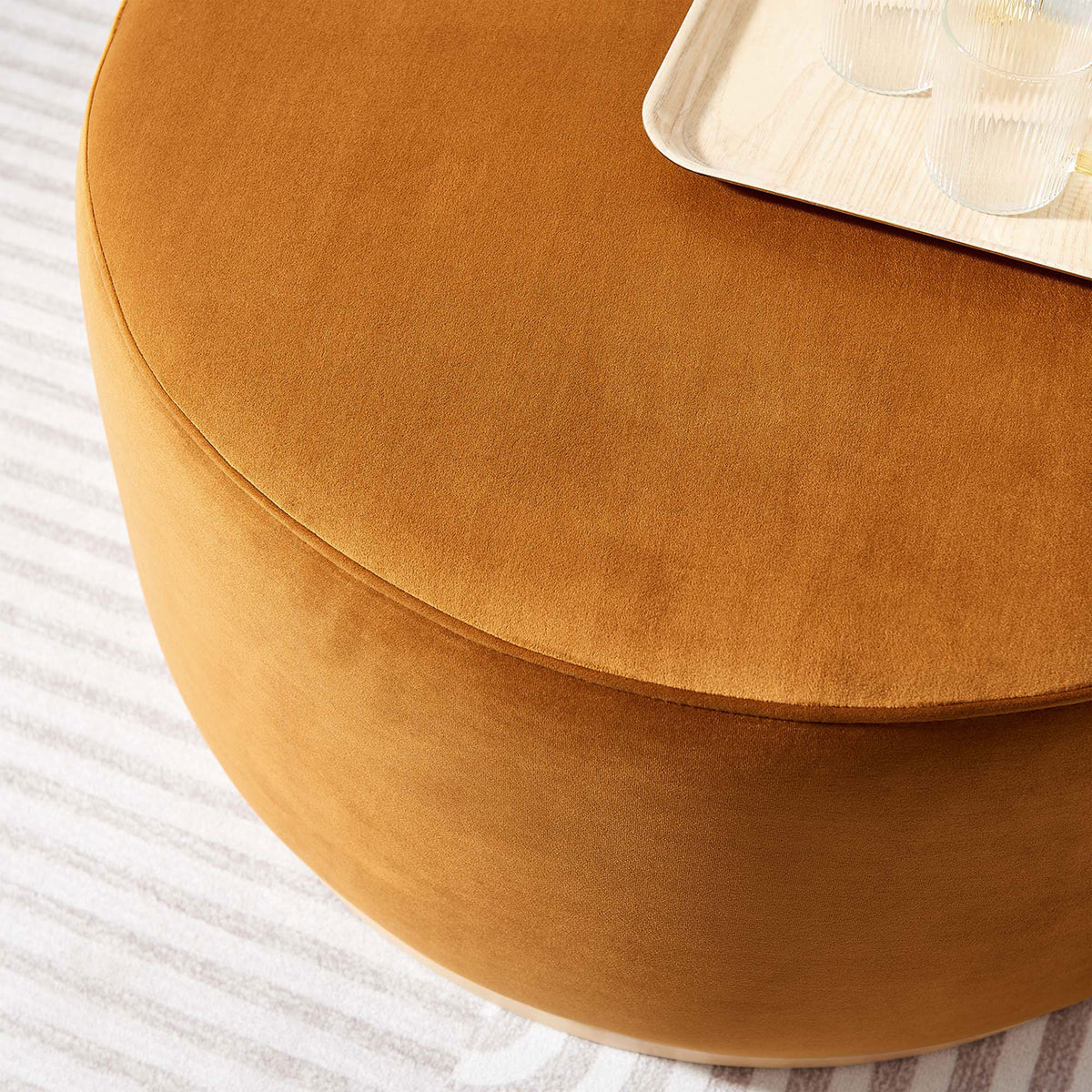 Rust velvet ottoman topped with tray and glasses, serving as a soft coffee table in living room. || EEI-6648-RUS-NAT || detail_room