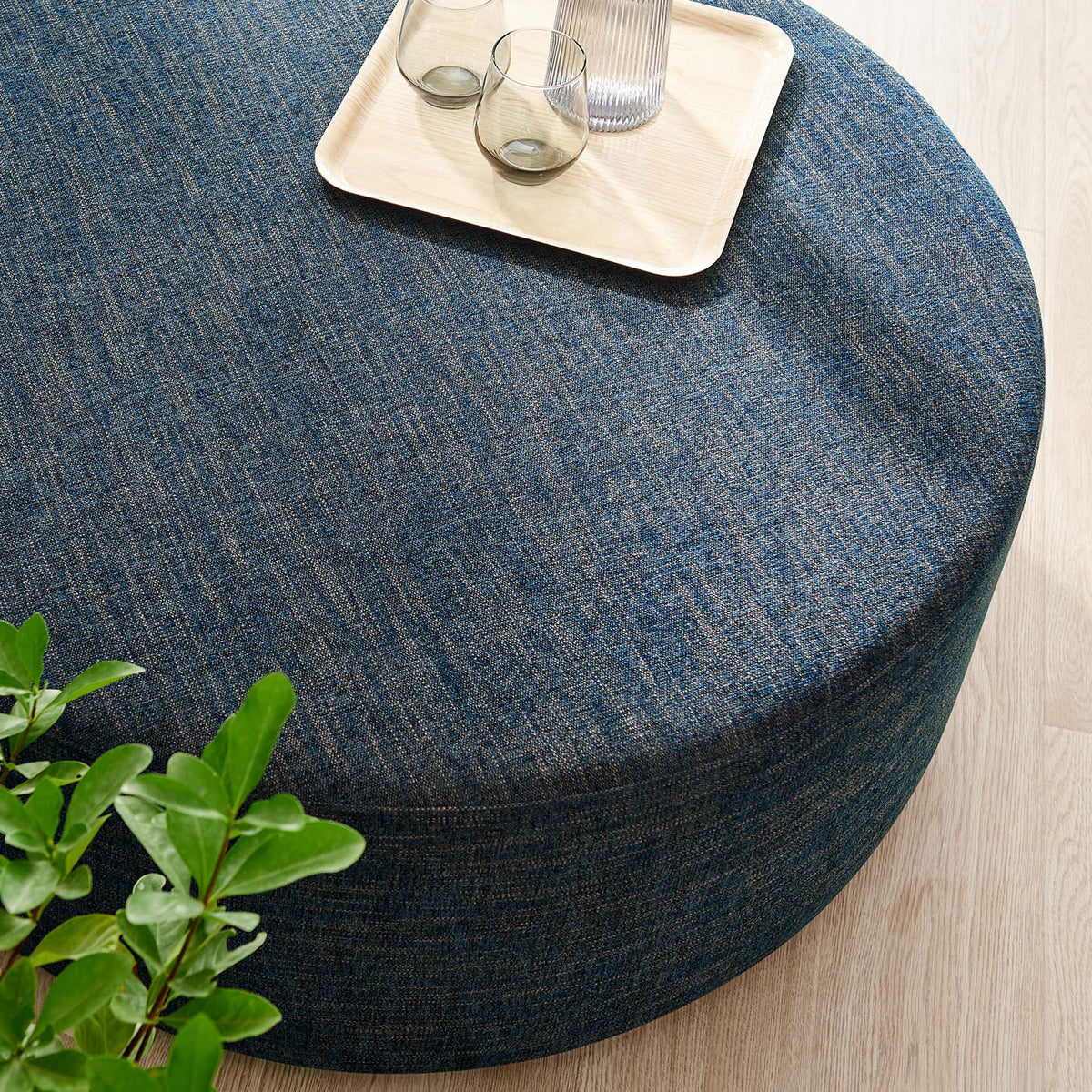 Generous cushioned top of the 38 inch round ottoman in heathered azure fabric styled with a tray || EEI-6649-HEA || top_angle_room