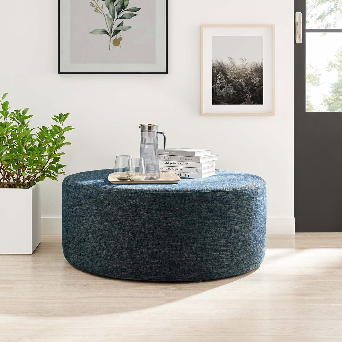 38 inch azure ottoman used as a coffee table in a bright living room with books, tray, and drinks on top || EEI-6649-HEA || front_angle_room