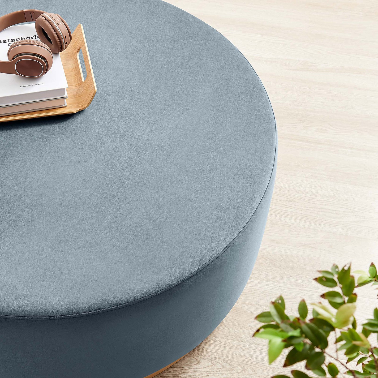 Spacious round velvet ottoman serving as a casual perch for a tray and headphones in a serene room || EEI-6650-CAB-NAT || detail_room