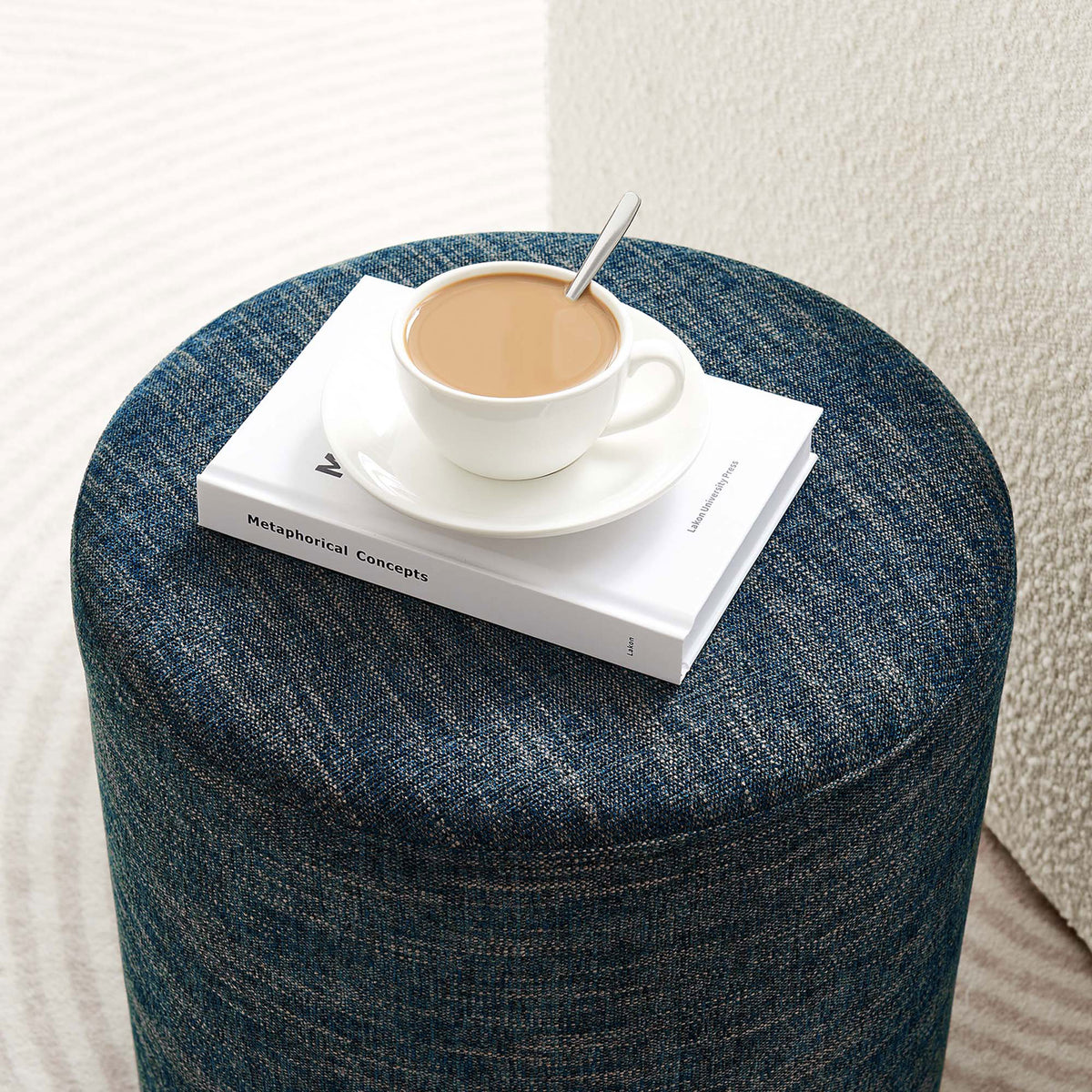 Callum ottoman doubles as a compact side table, holding coffee and books in a modern living room || EEI-6651-HEA || front_angle_room