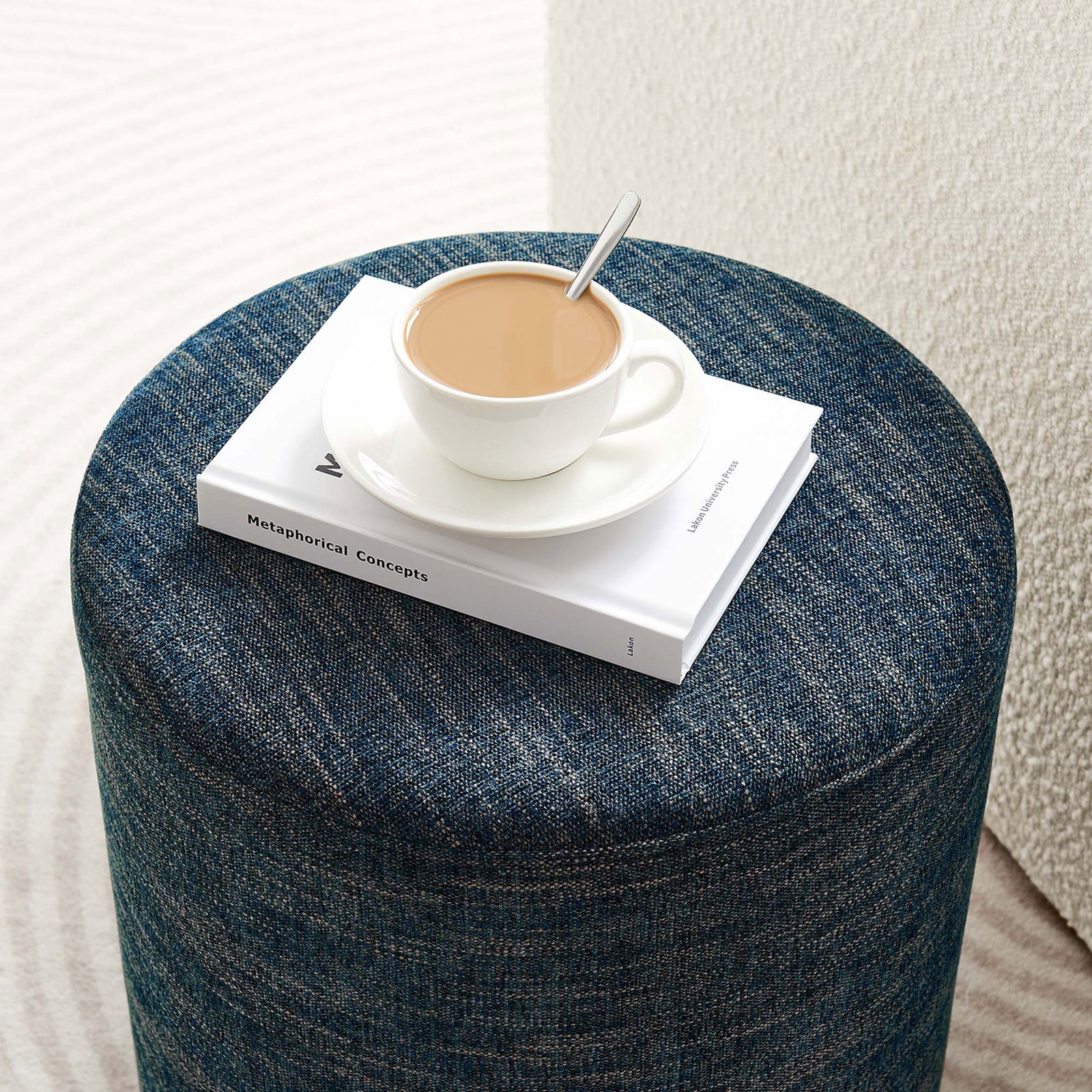 Callum ottoman doubles as a compact side table, holding coffee and books in a modern living room || EEI-6651-HEA || front_angle_room