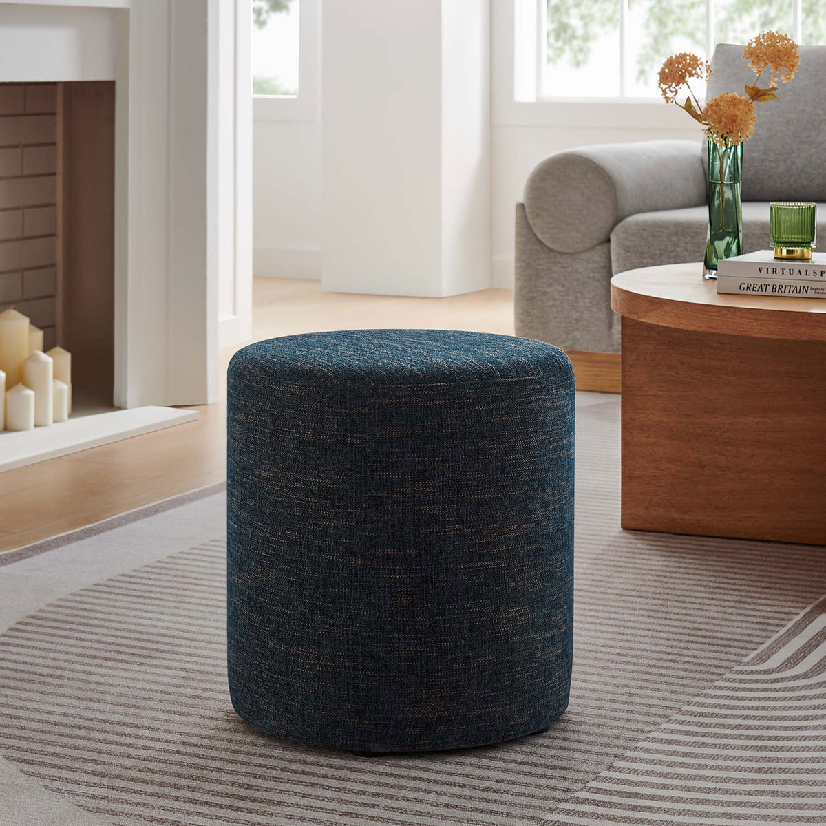 Round azure ottoman completes a modern seating area, offering versatile use as a seat, table, or footrest || EEI-6651-HEA || front_angle_room