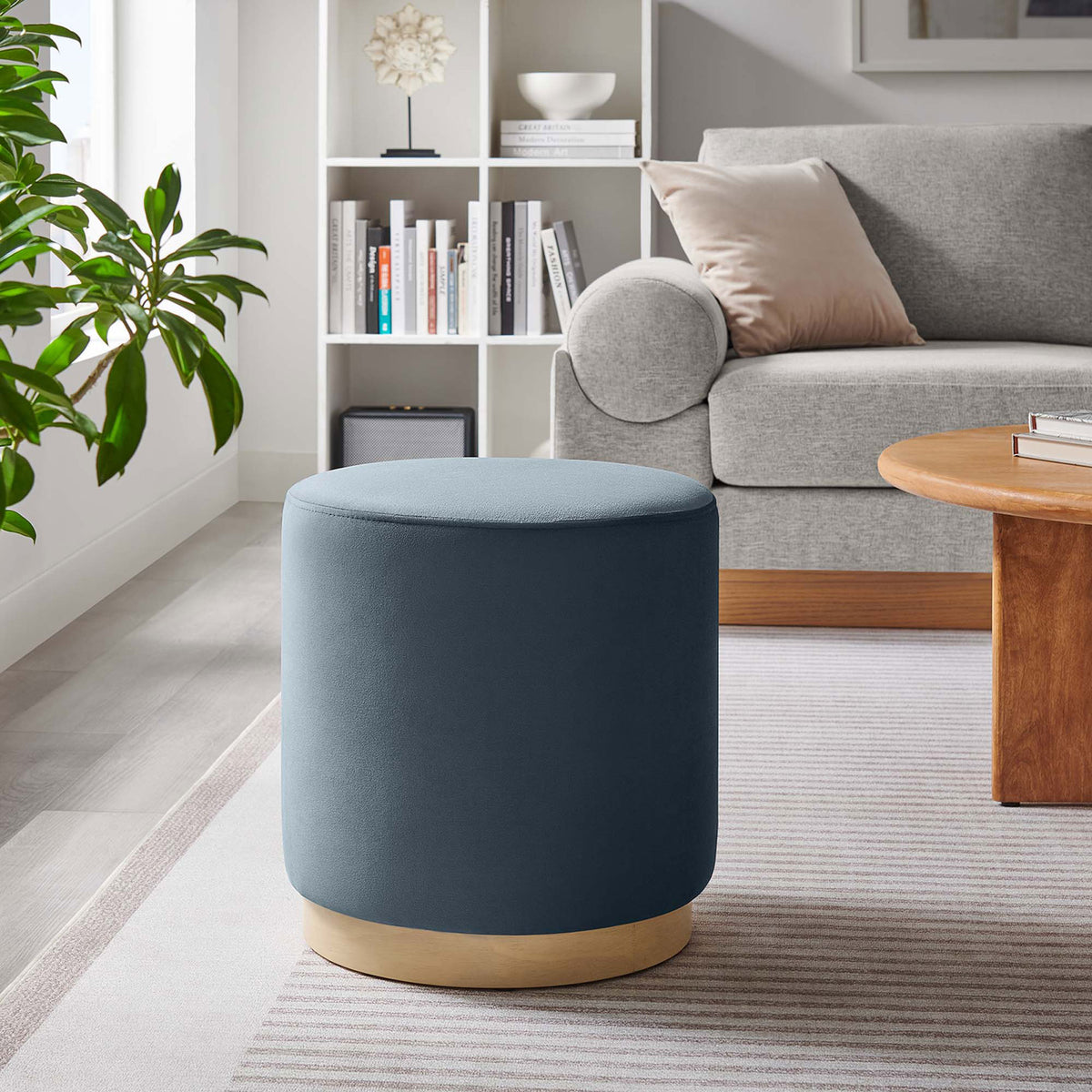 Blue velvet ottoman with natural wood base in a contemporary living space || EEI-6652-CAB-NAT || front_angle_room