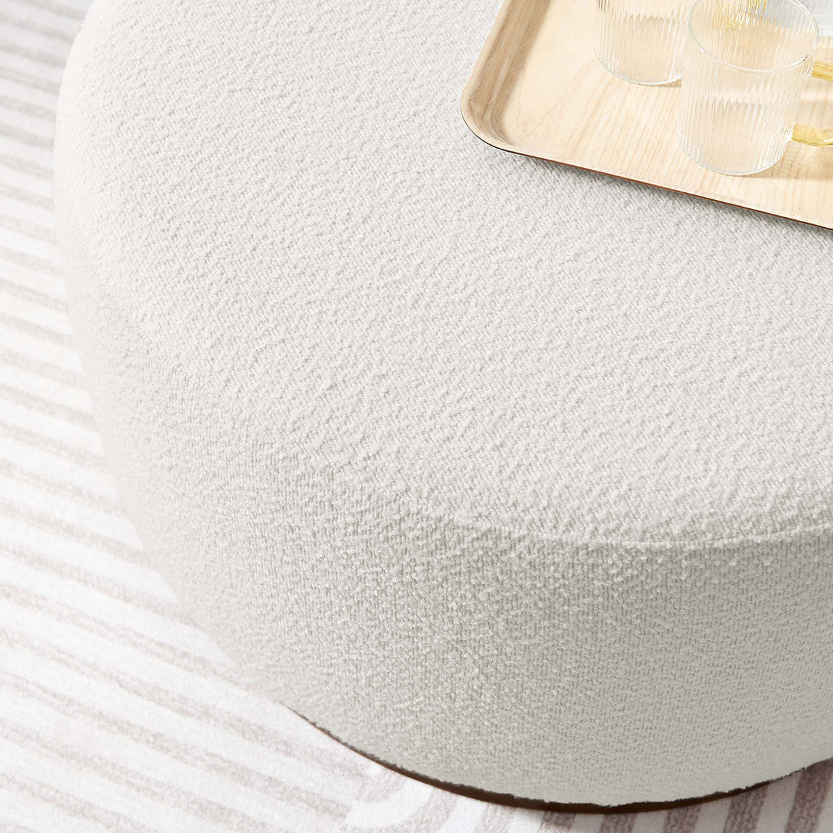 Boucle ottoman used as a coffee table with tray and glassware on a striped rug || EEI-6681-CLO-WAL || detail_room