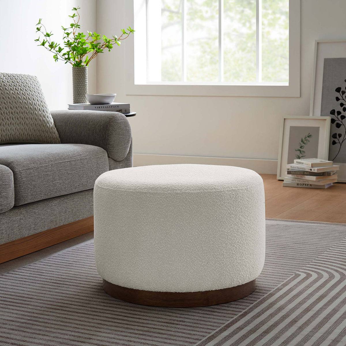 Compact round boucle ottoman with walnut base accenting a modern living room with gray sofa and rug || EEI-6683-CLO-WAL || front_angle_room