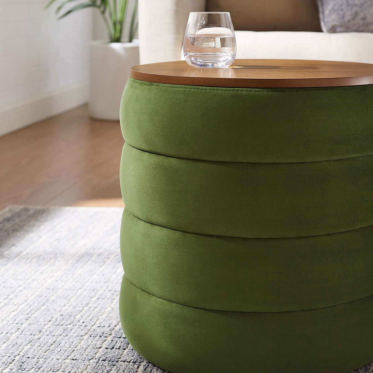 Moss green velvet storage ottoman styled as a side table beside a sofa with a drink resting on the lid || EEI-6684-MOG || detail_room