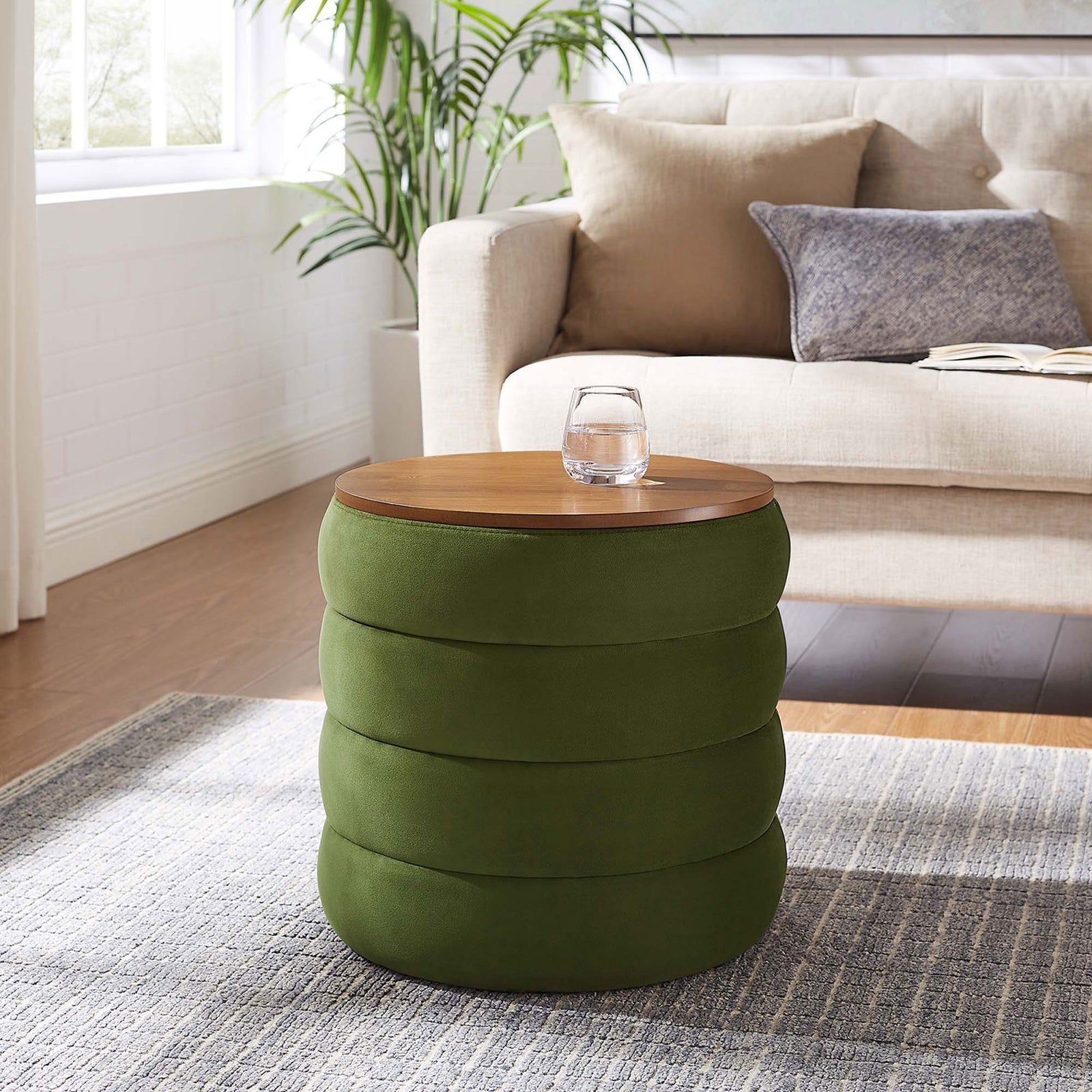 Round moss green storage ottoman adds a pop of color beside a neutral sofa in a bright living room || EEI-6684-MOG || front_angle_room
