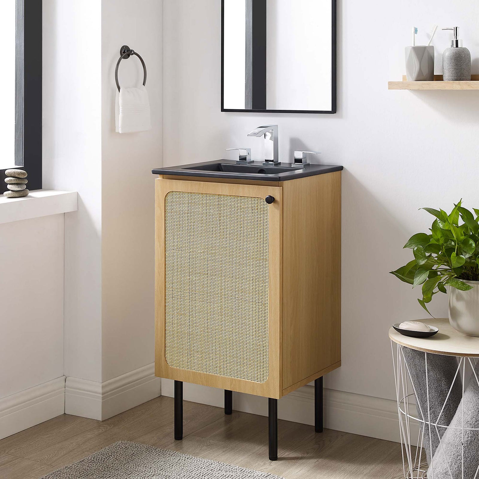 Space-saving vanity elevates any bath with airy legs, textured rattan, and a matte black sink || EEI-6692-OAK-BLK || front_angle_room