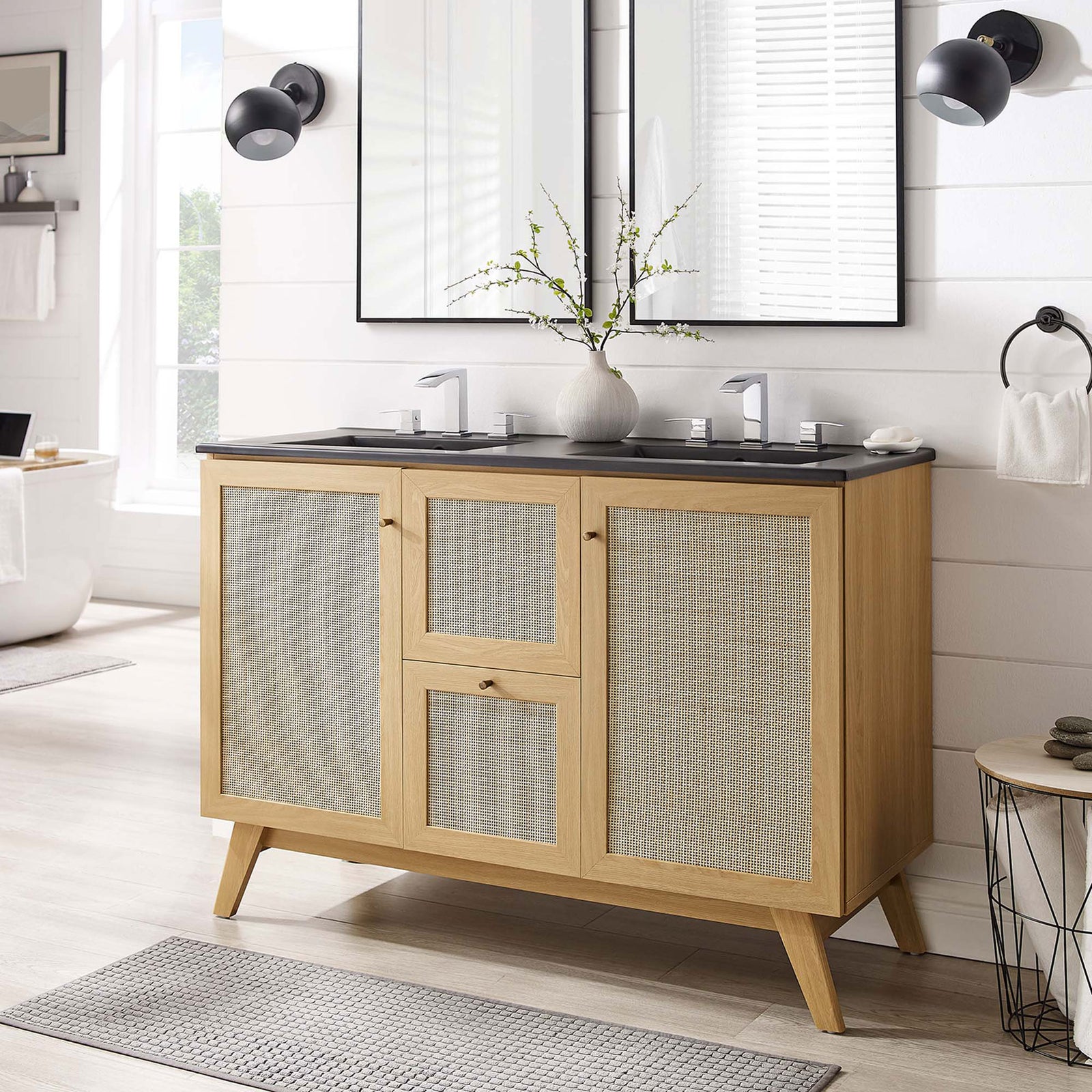 Warm oak and rattan vanity creates a calm focal point with a sleek black dual sink || EEI-6722-OAK-BLK || front_angle_room