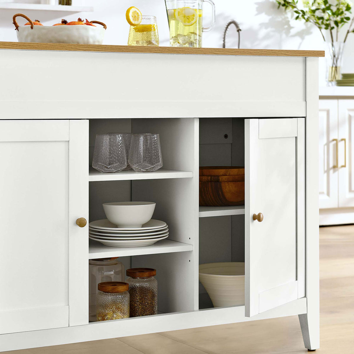 Kitchen island styled with glassware, dinnerware, and pantry jars to showcase practical everyday storage || EEI-6727-OAK-WHI || storage_open_room