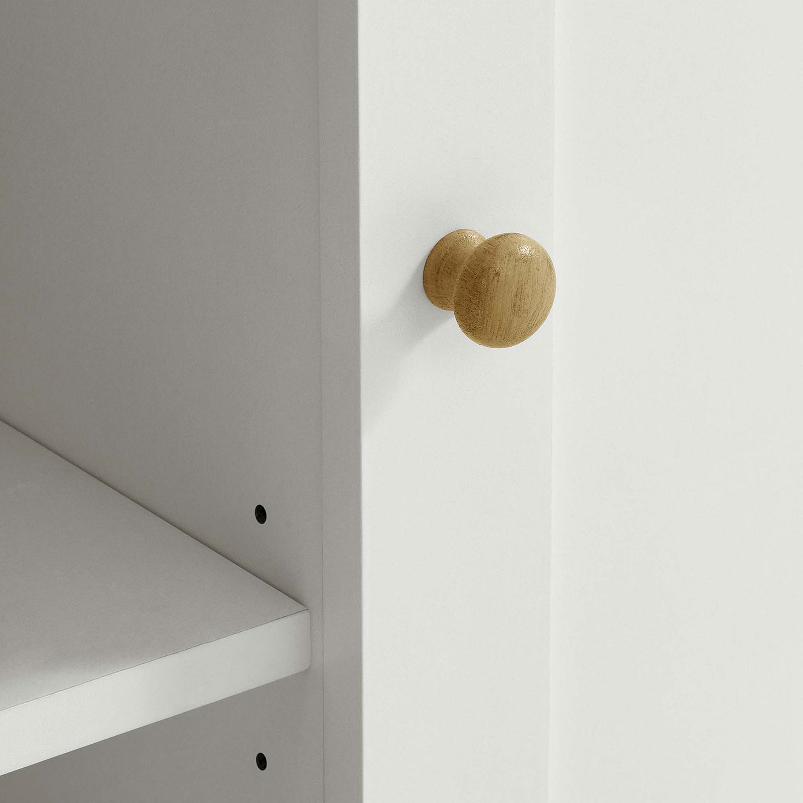 Round oak-finished cabinet knob contrasted against the smooth white frame of the kitchen island || EEI-6727-OAK-WHI || handle_studio