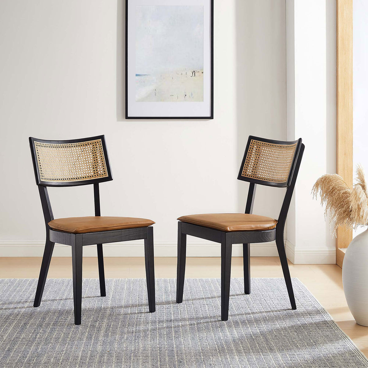 Set of two black wood dining chairs with tan vegan leather seats and rattan backs in a bright dining room || EEI-6732-BLK-TAN || front_angle_multi_room