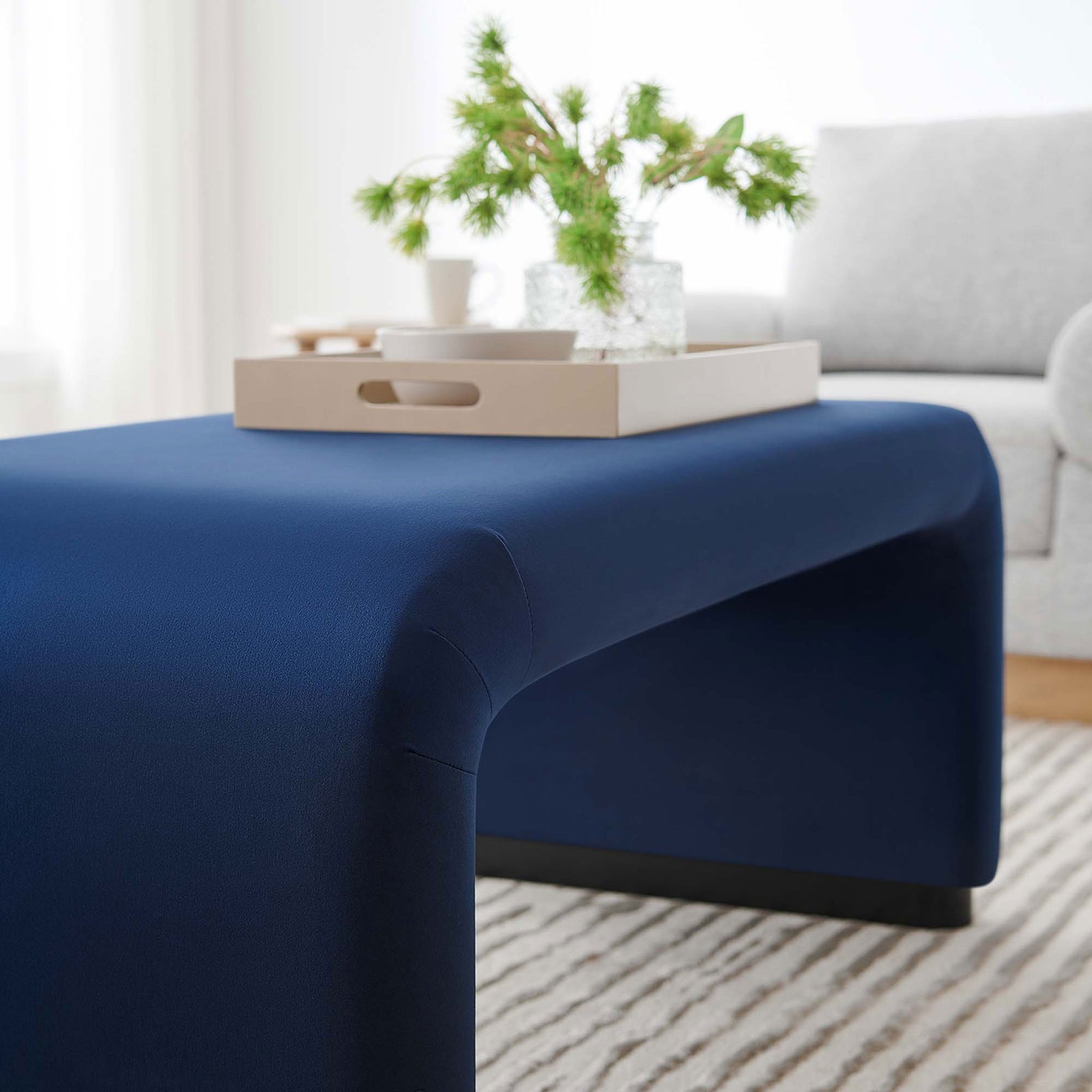 Styled close-up of the ottoman used as a coffee table with a tray and decor in a bright living room || EEI-6735-BLK-MID || detail_room