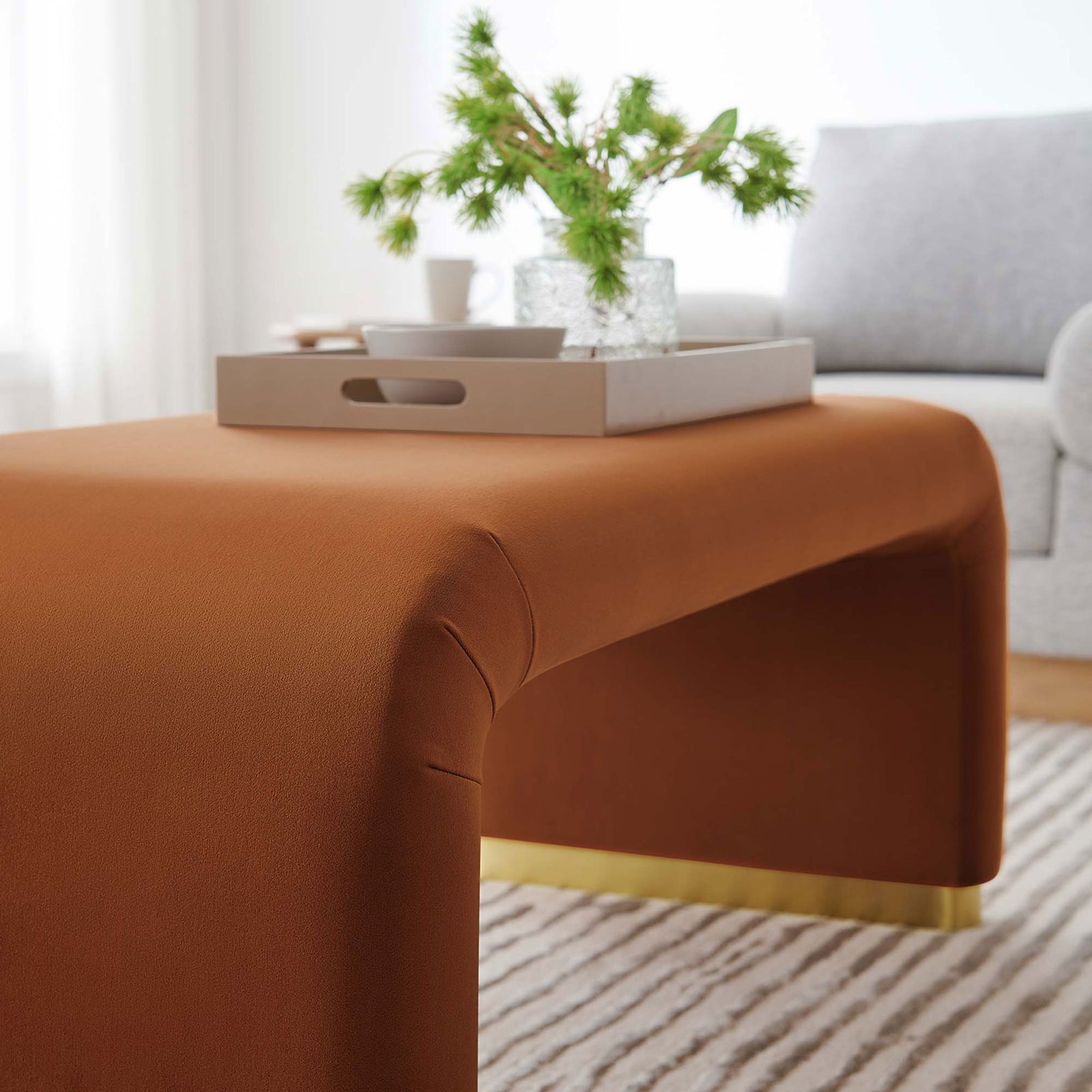 Brass rust waterfall ottoman styled with a tray and decor in a cozy light-filled living room || EEI-6735-BRA-RUS || detail_room