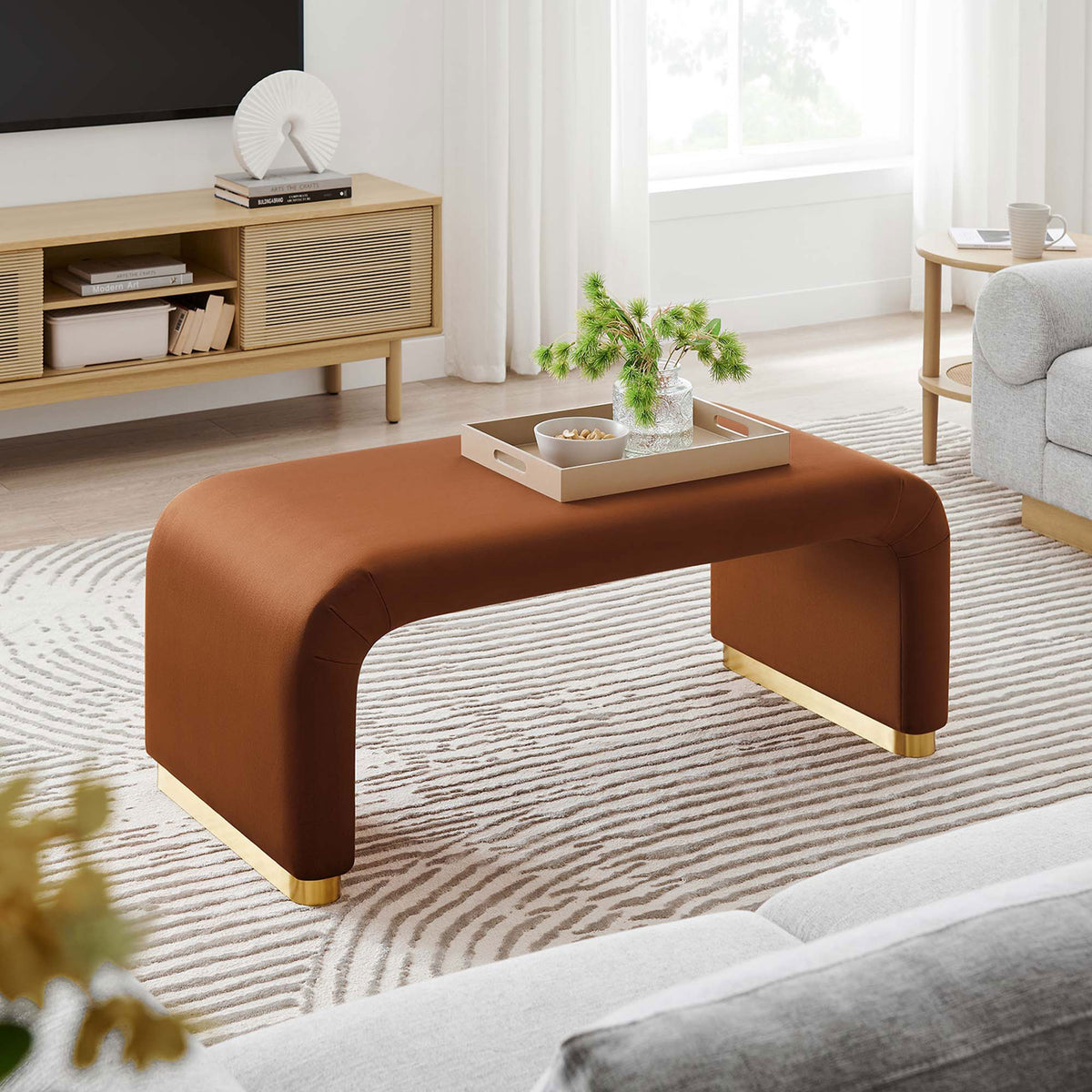 Brass rust velvet waterfall ottoman used as a coffee table in a modern living room setting || EEI-6735-BRA-RUS || front_angle_room