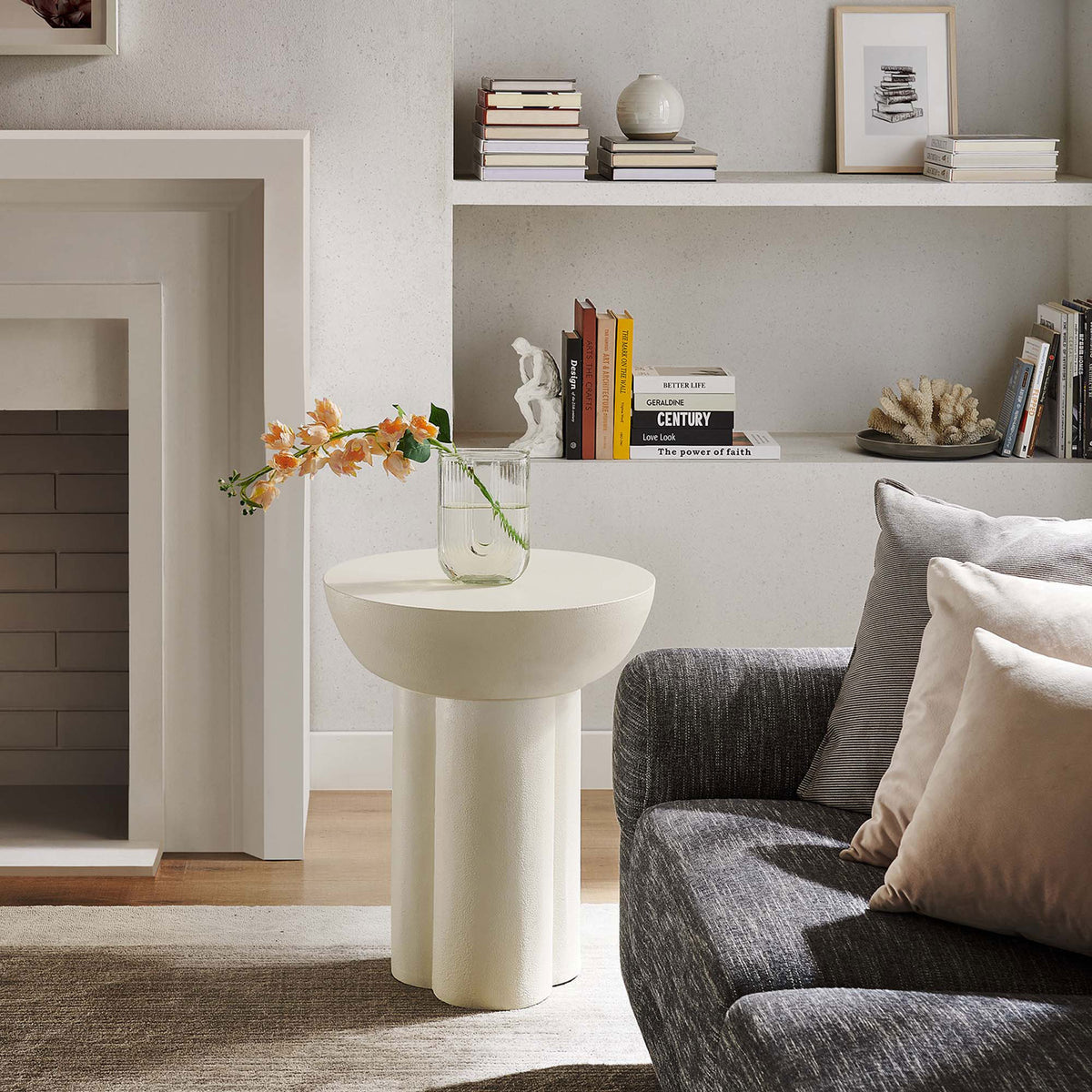 Caspian white round side table anchors a serene living room with its sculptural pedestal base and clean silhouette || EEI-6761-WHI || front_angle_room
