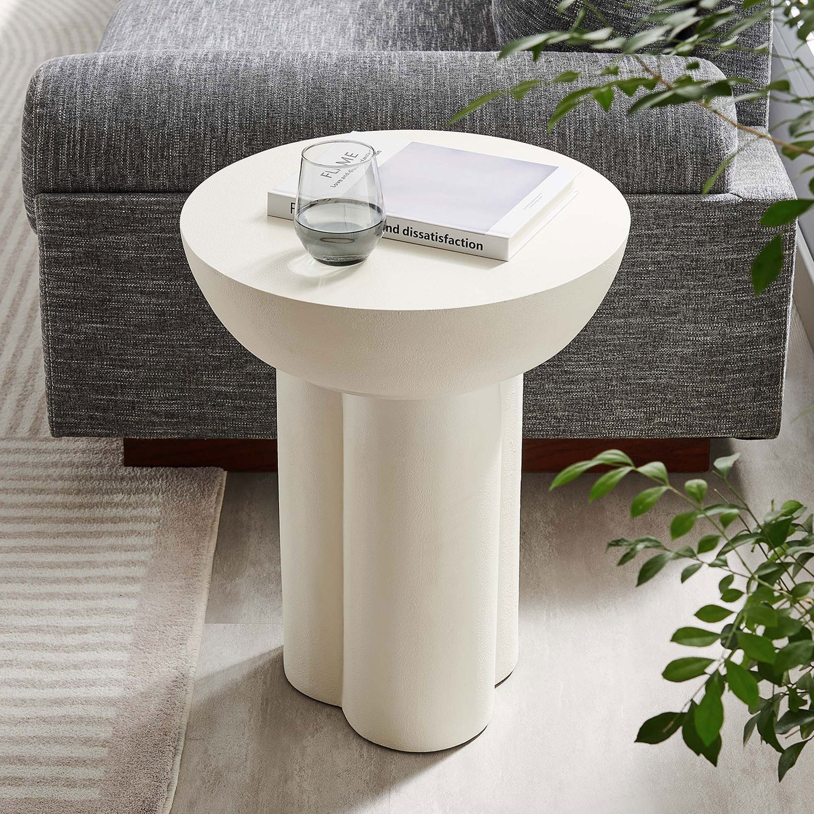 White round concrete side table beside a sofa, perfect for holding drinks, decor, and everyday essentials || EEI-6761-WHI || front_angle_room