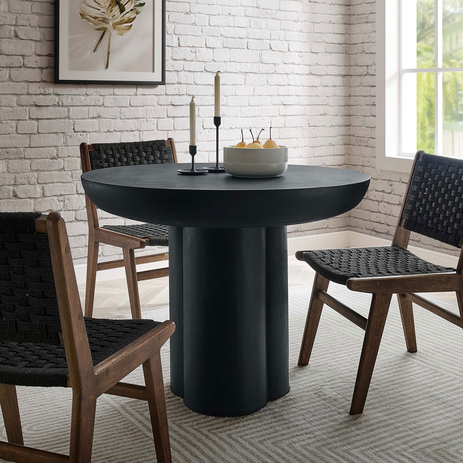 Black pedestal dining table anchored by woven chairs in a cozy brick walled breakfast area || EEI-6762-BLK || front_angle_room