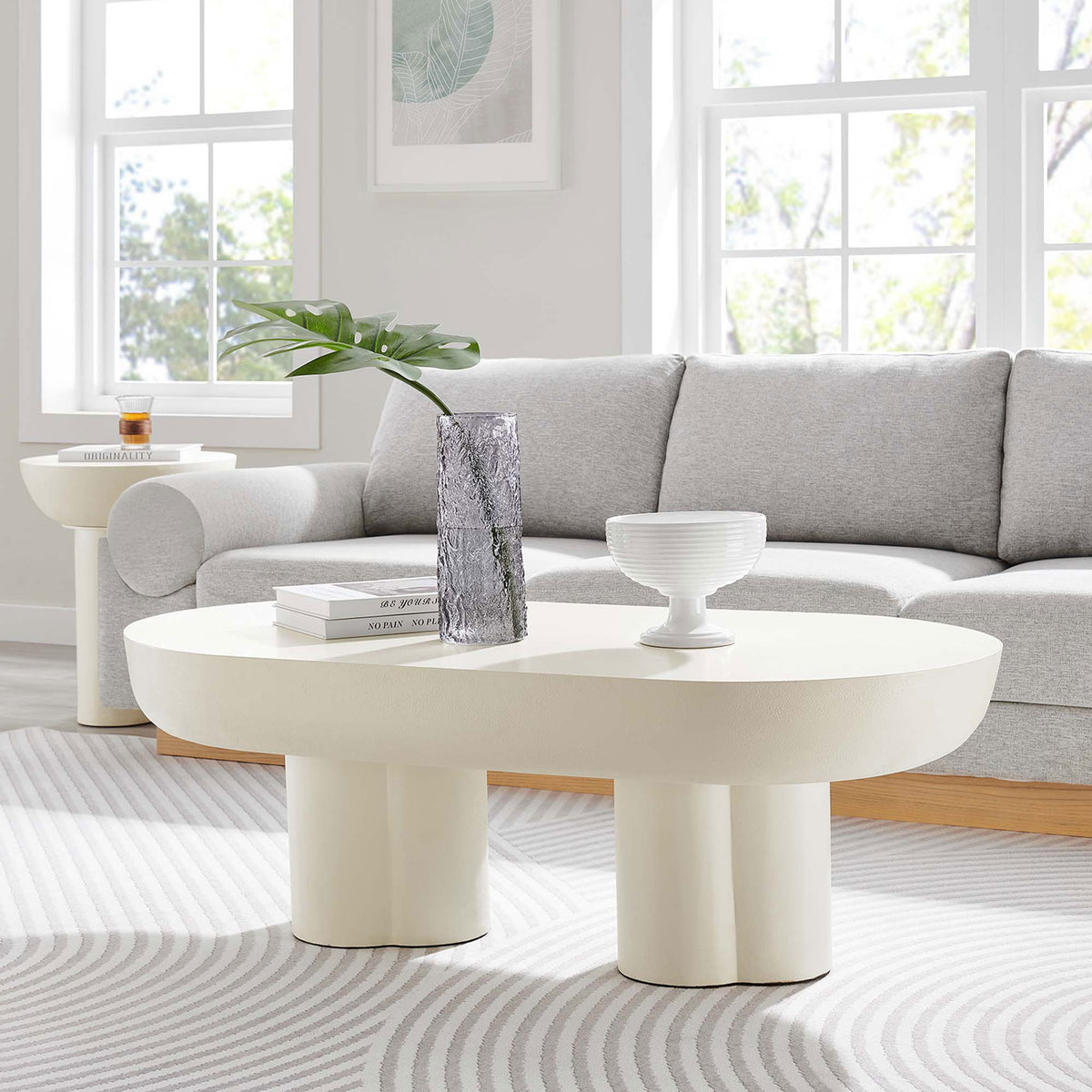 Modern oval coffee table anchors the seating area with bold curves and a thick, sculptural silhouette || EEI-6763-WHI || front_angle_room