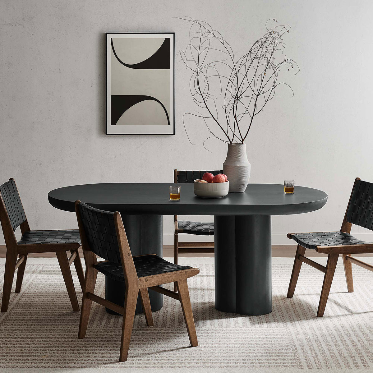 Black oval dining table paired with woven strap chairs and modern graphic wall art || EEI-6764-BLK || front_angle_room