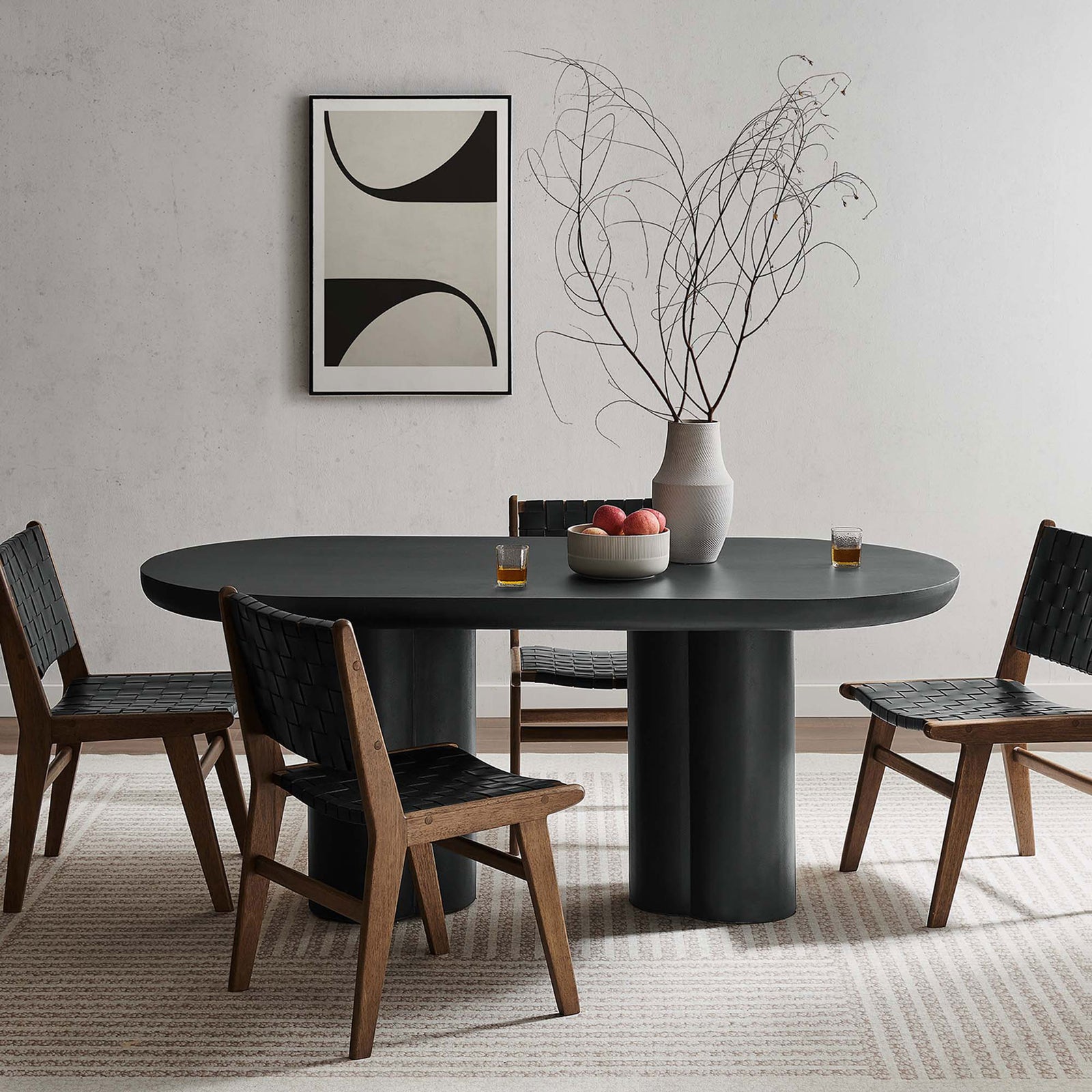 Black oval dining table paired with woven strap chairs and modern graphic wall art || EEI-6764-BLK || front_angle_room
