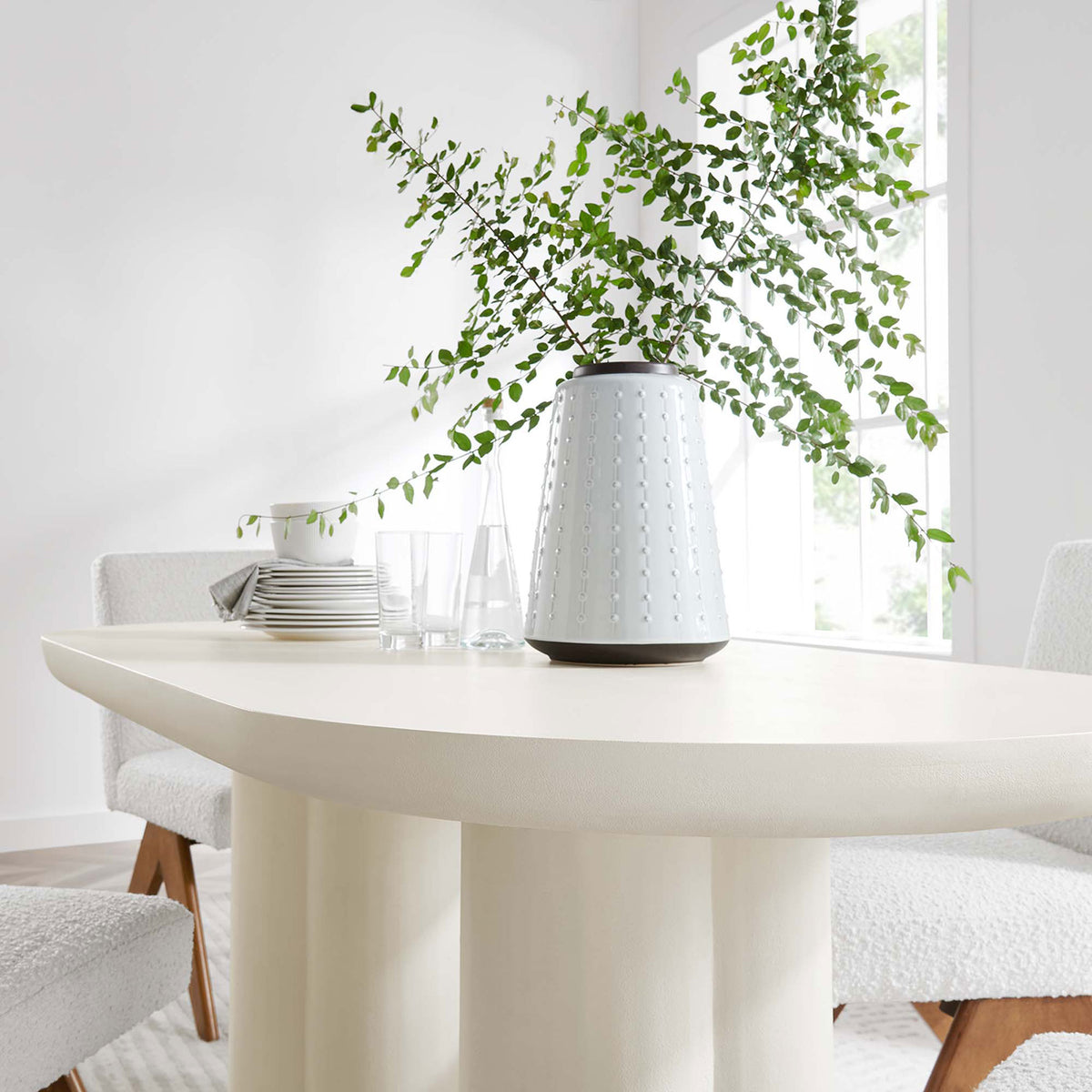 White concrete dining table styled with modern chairs, glassware, and a tall ceramic vase || EEI-6764-WHI || detail_room