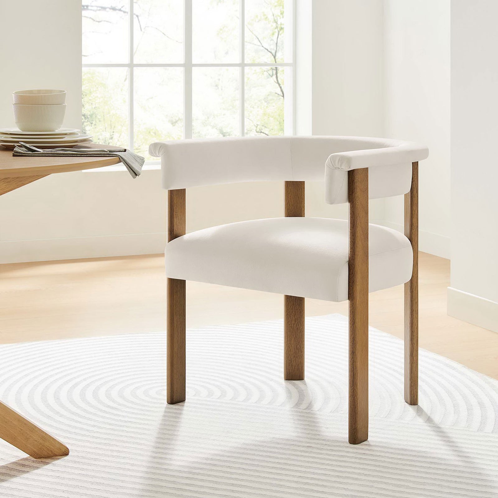 Alabaster velvet dining chair with barrel back pairs beautifully with a light wood table and airy rug. || EEI-6775-ALA-DBR || front_angle_partial_room