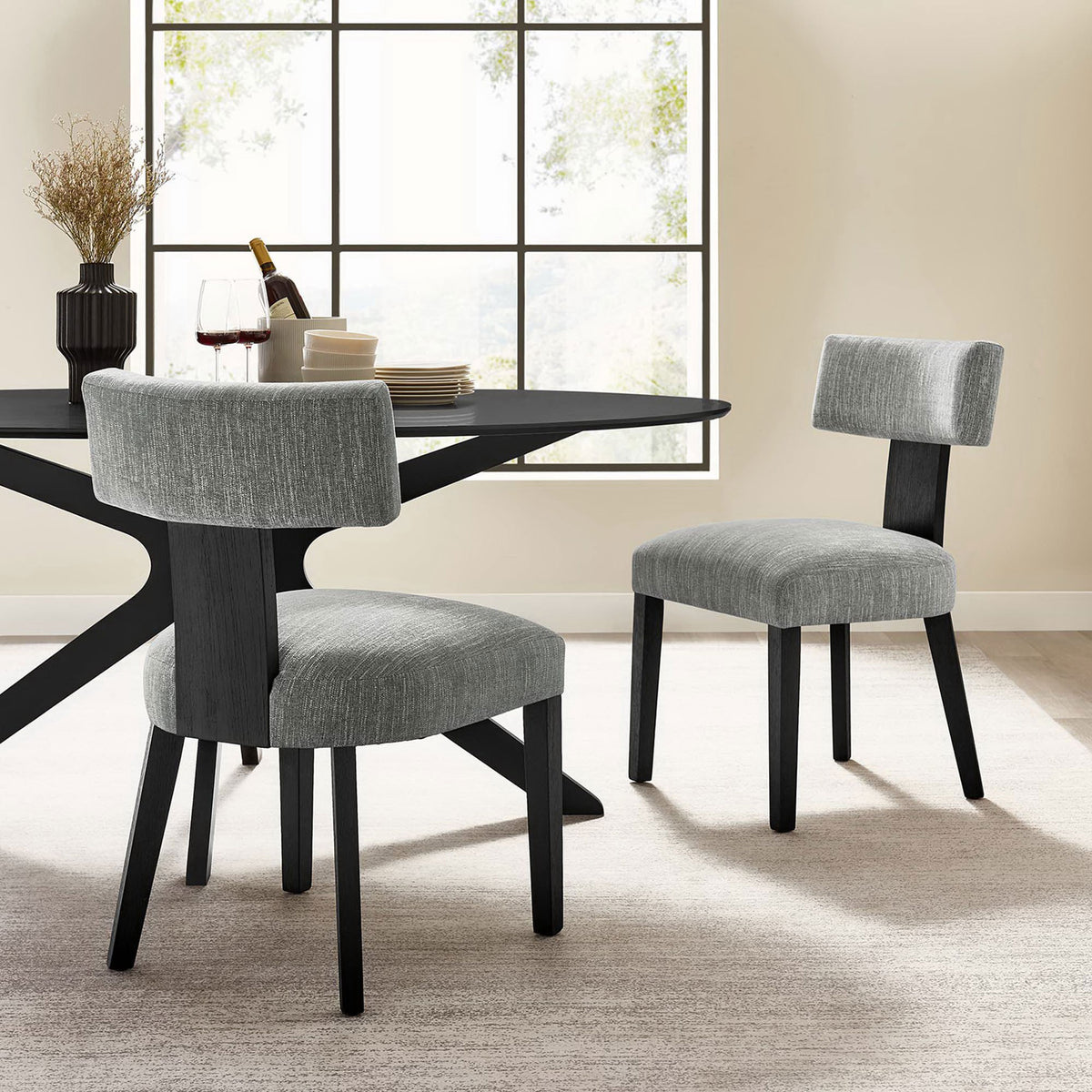Pair of gray fabric dining chairs around a modern black dining table in a bright airy room || EEI-6777-HEG-BLK || front_angle_multi_room