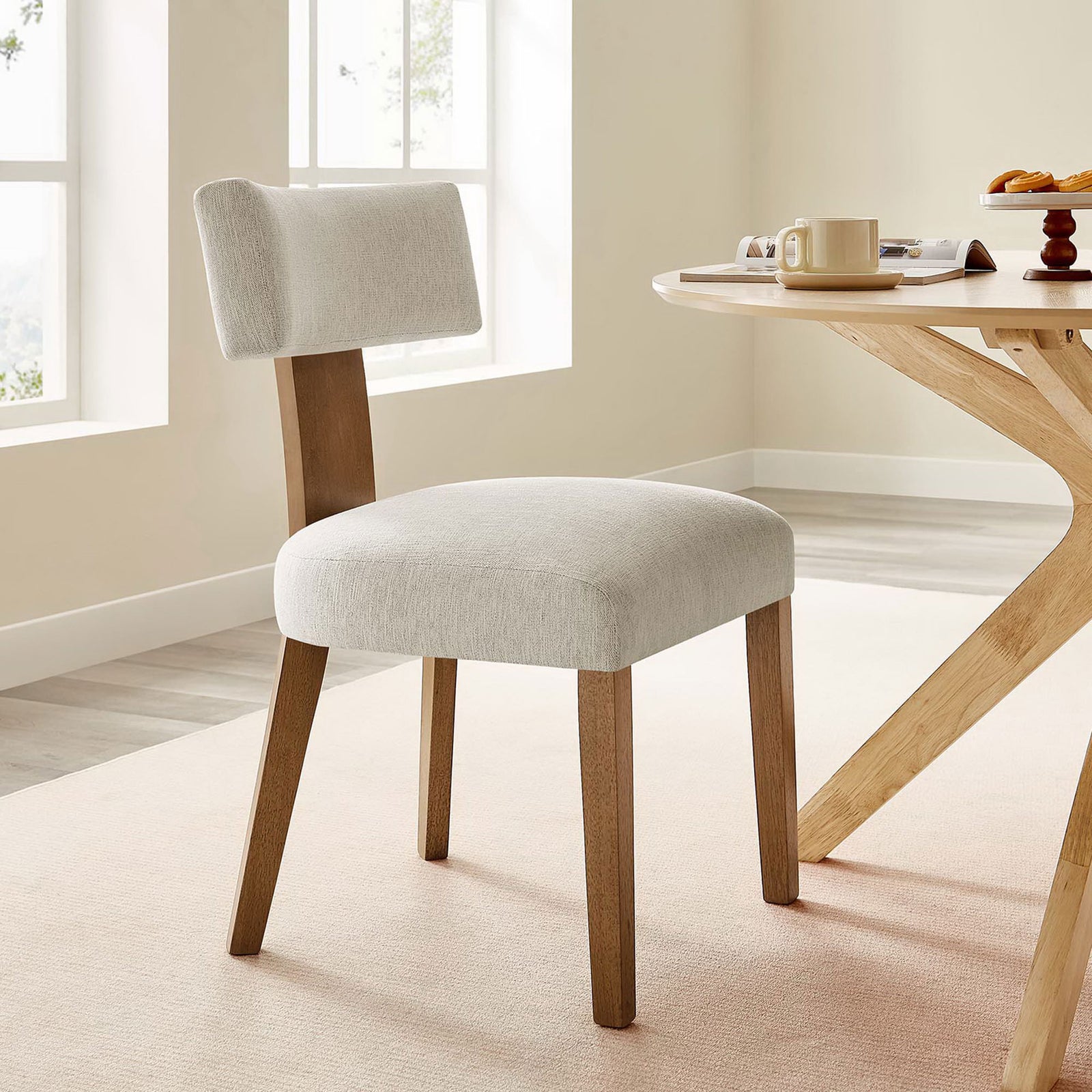 Ivory upholstered dining chair paired with a light wood table in an airy dining space. || EEI-6777-HEI-DBR || front_angle_room