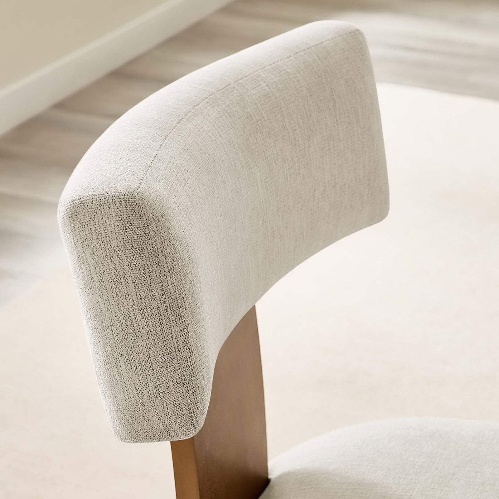 Curved ivory backrest of the dining chair styled in a bright modern dining room. || EEI-6777-HEI-DBR || detail_room