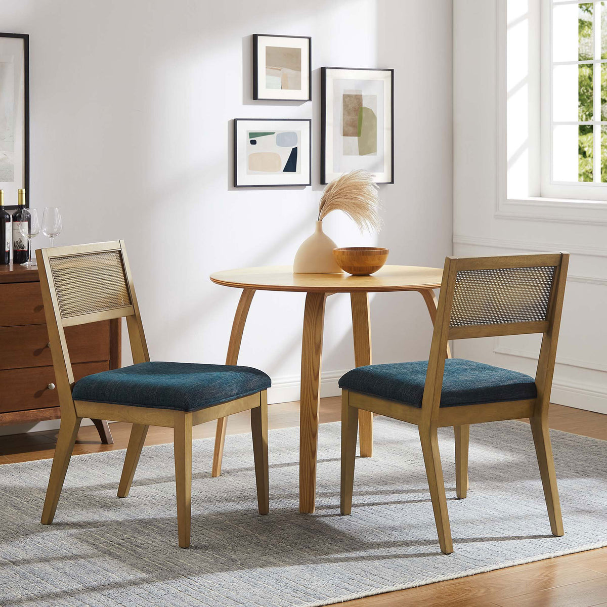 Pair of Nimba dining chairs around a round table, blending cane backs and blue seats into a cozy dining space || EEI-6781-FRO-HEA || front_angle_multi_room