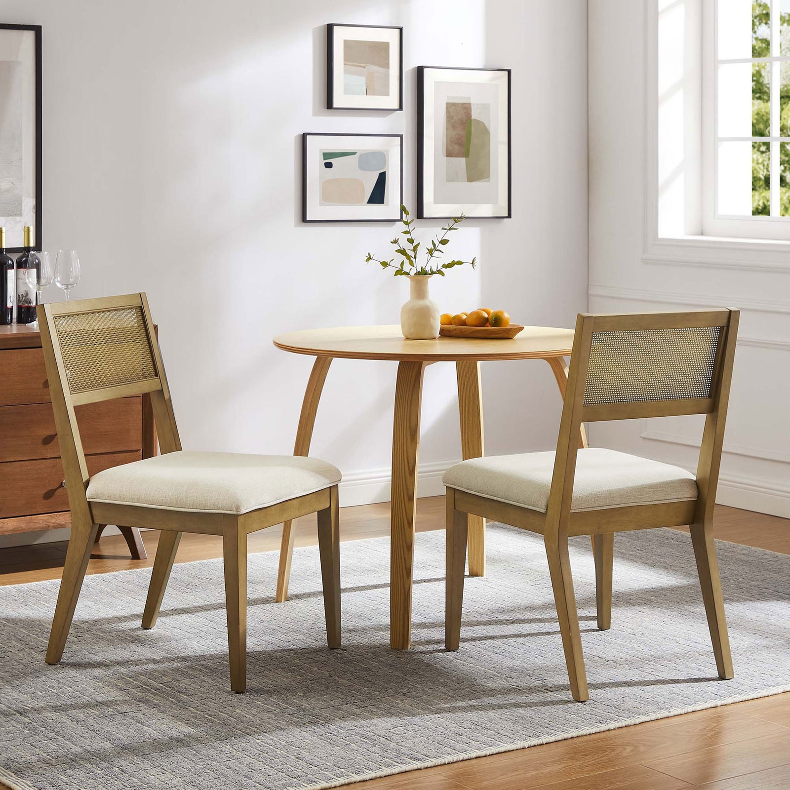Pair of faux rattan dining chairs around a round table creating a cozy breakfast nook || EEI-6781-FRO-HEI || front_angle_multi_room